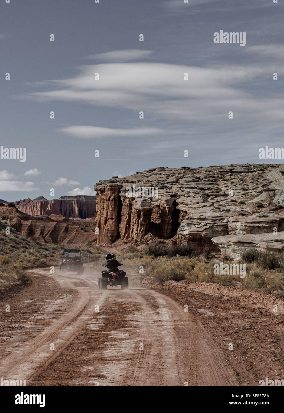 Guidatori di quad su una strada sterrata che si snoda attraverso un paesaggio desertico di rocce rosse. Foto Stock