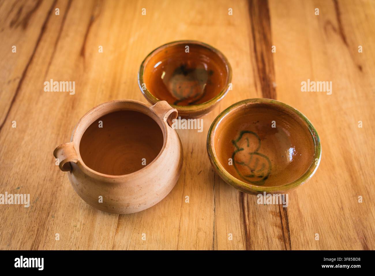 Primo piano di una ceramica andina con una pentola di argilla e piatti su un tavolo di legno rustico Foto Stock