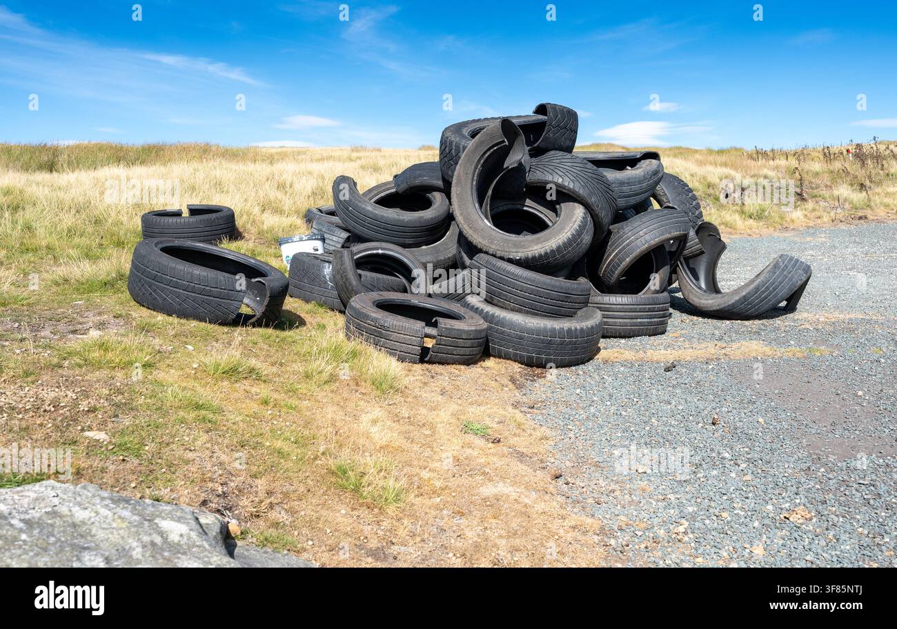 Cumulo di vecchi pneumatici per auto abbandonati su un lato della strada rurale nelle Yorkshire Dales, causando un rischio di inquinamento. Foto Stock