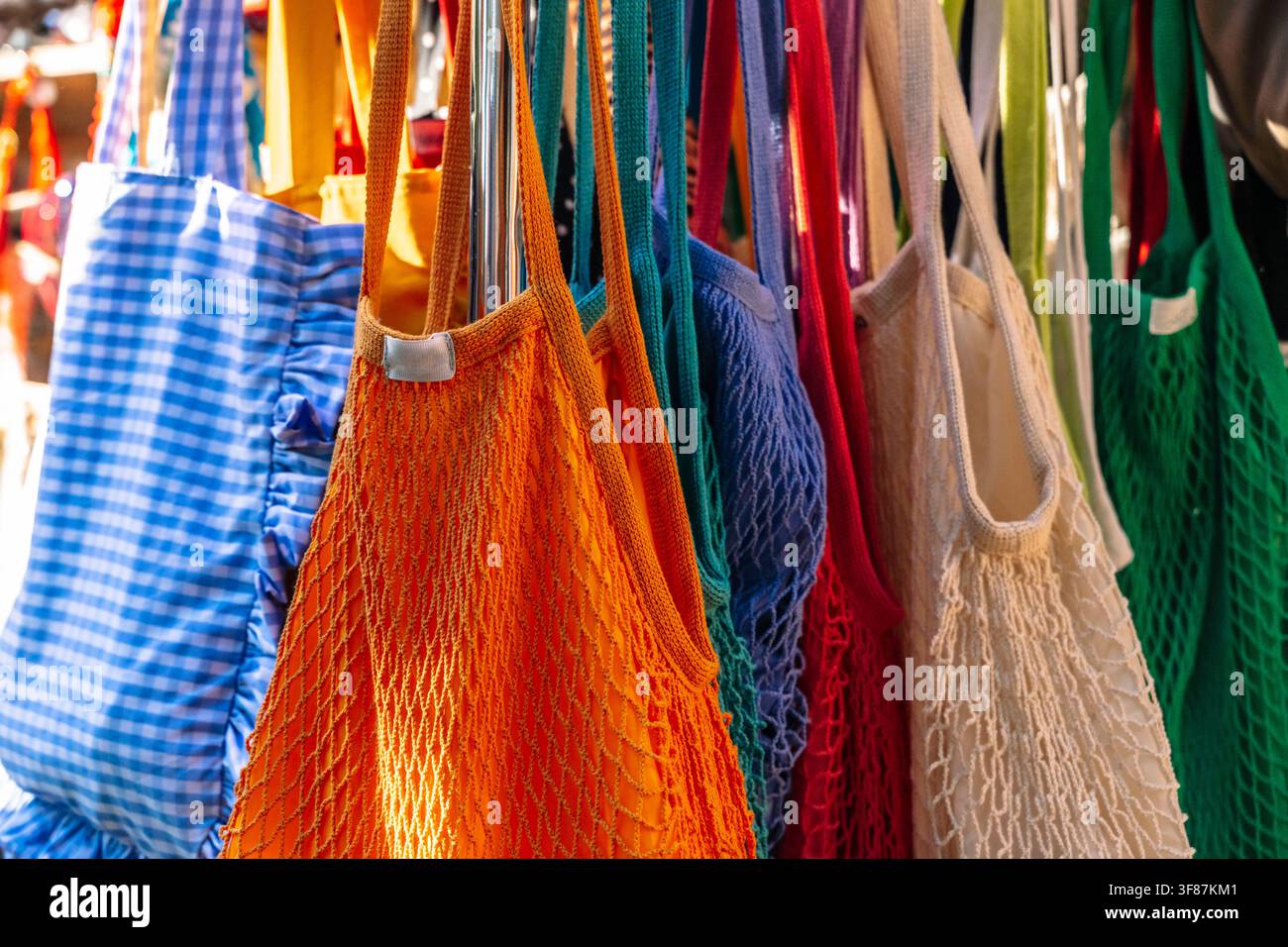 Borse riutilizzabili colorate in rete e tessuto appese a una rastrelliera espositiva. Foto di alta qualità Foto Stock