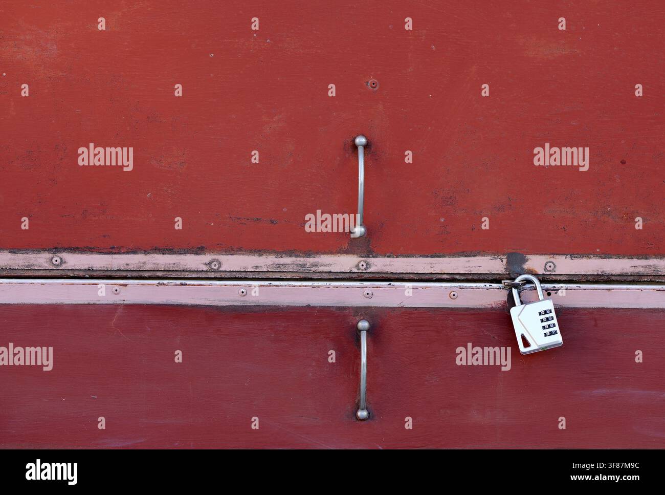Porta metallica rossa con maniglie e una serratura a combinazione moderna, che evidenzia temi di sicurezza, accesso, protezione e texture industriale Foto Stock