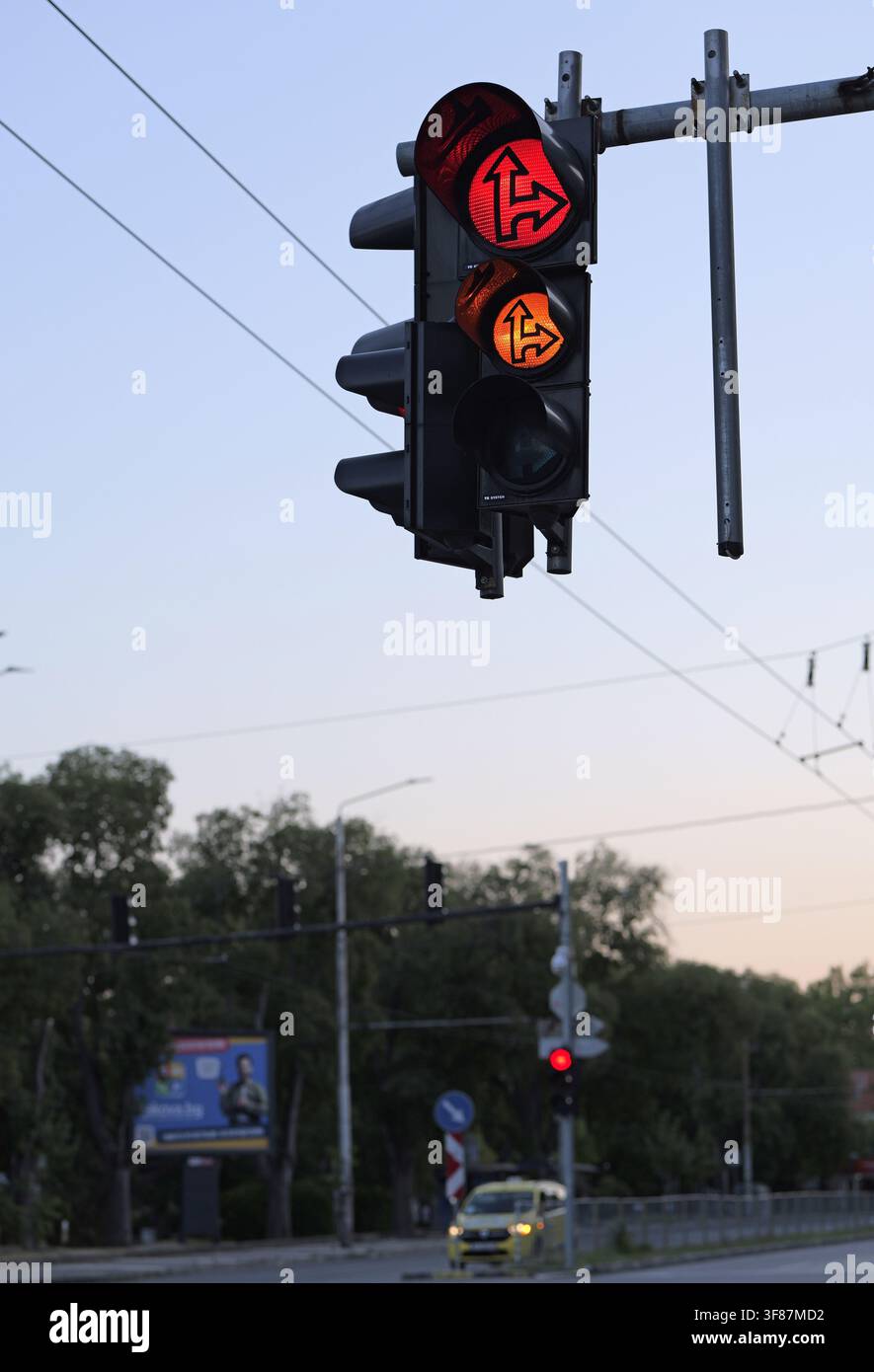 Semaforo con frecce rosse e ambrate illuminate che forniscono segnali direzionali complessi per i veicoli su una strada cittadina, controllando il flusso e garantendo la sicurezza Foto Stock