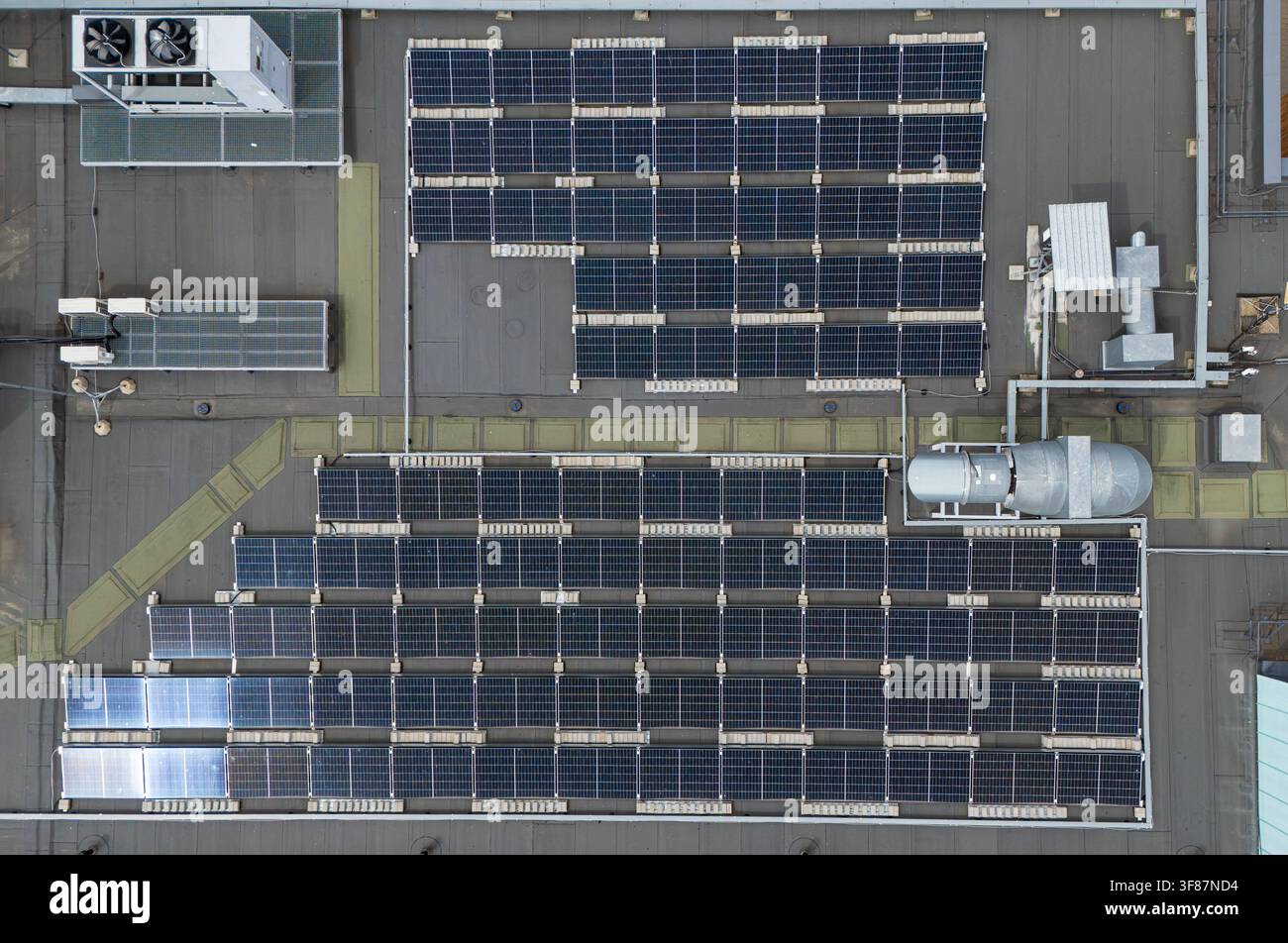 Vista aerea dall'alto di array di pannelli solari e apparecchiature HVAC su un tetto industriale piatto, energia rinnovabile commerciale e infrastruttura edilizia Foto Stock