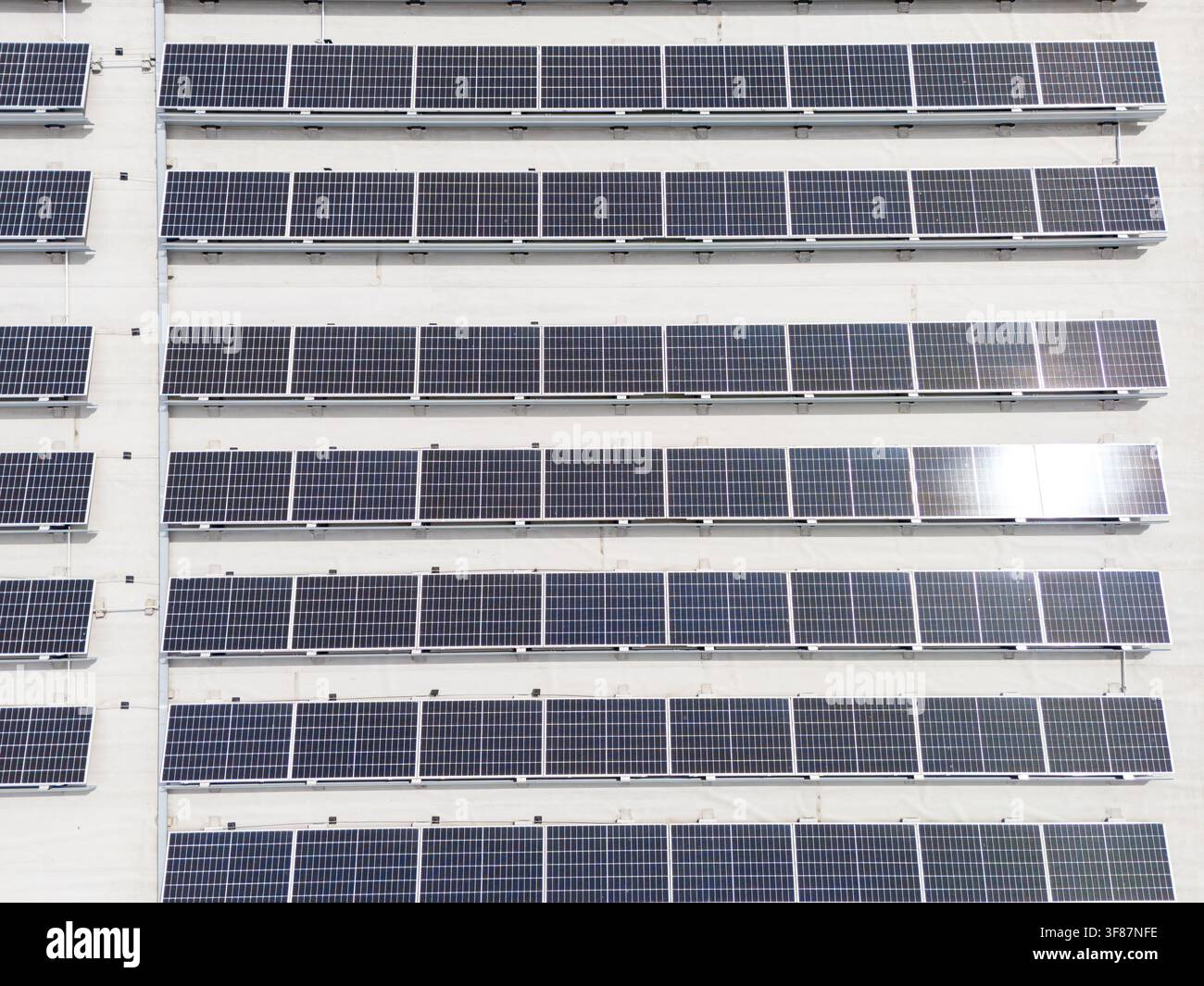 Panelli solari montati in file uniformi sulla facciata dell'edificio, installazione fotovoltaica innovativa e concetto di energia rinnovabile. Foto Stock