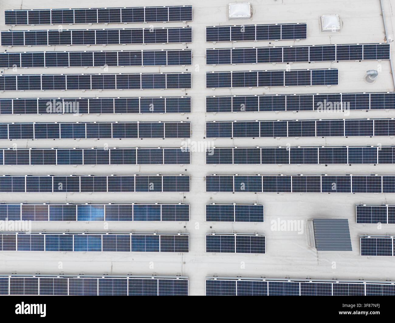 Vista aerea ravvicinata di un grande array di pannelli solari disposti in file diagonali su un tetto piatto commerciale, infrastruttura di energia rinnovabile e fotovoltaico Foto Stock
