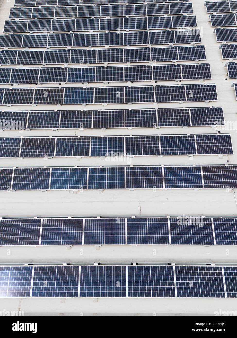 Vista aerea ravvicinata di un grande array di pannelli solari disposti in file diagonali su un tetto piatto commerciale, infrastruttura di energia rinnovabile e fotovoltaico Foto Stock