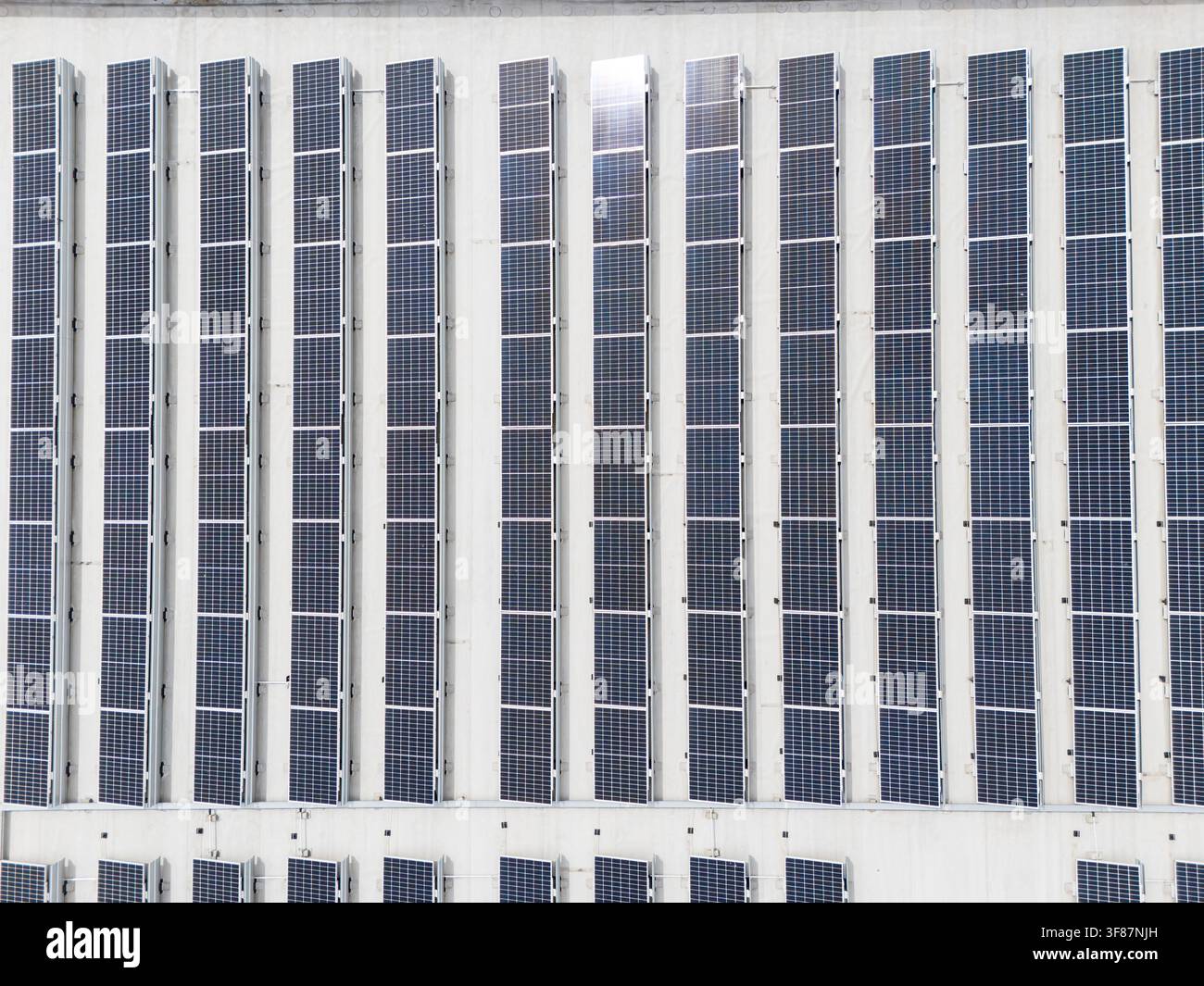 Panelli solari montati in file uniformi sulla facciata dell'edificio, installazione fotovoltaica innovativa e concetto di energia rinnovabile. Foto Stock