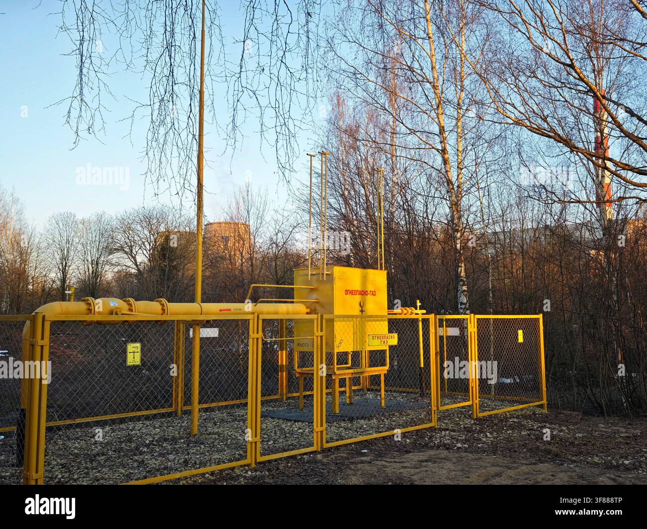 Pipeline di gas naturale giallo con grande valvola di intercettazione in una stazione di servizio recintata. Concetto di distribuzione del gas, infrastruttura e approvvigionamento energetico. Foto Stock