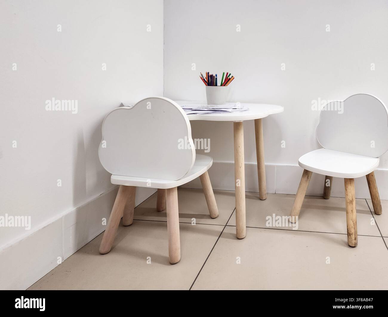 Set di mobili minimalisti per bambini con due iconiche sedie a forma di nuvola bianca e un tavolino. Offre uno spazio dedicato per attività creative Foto Stock
