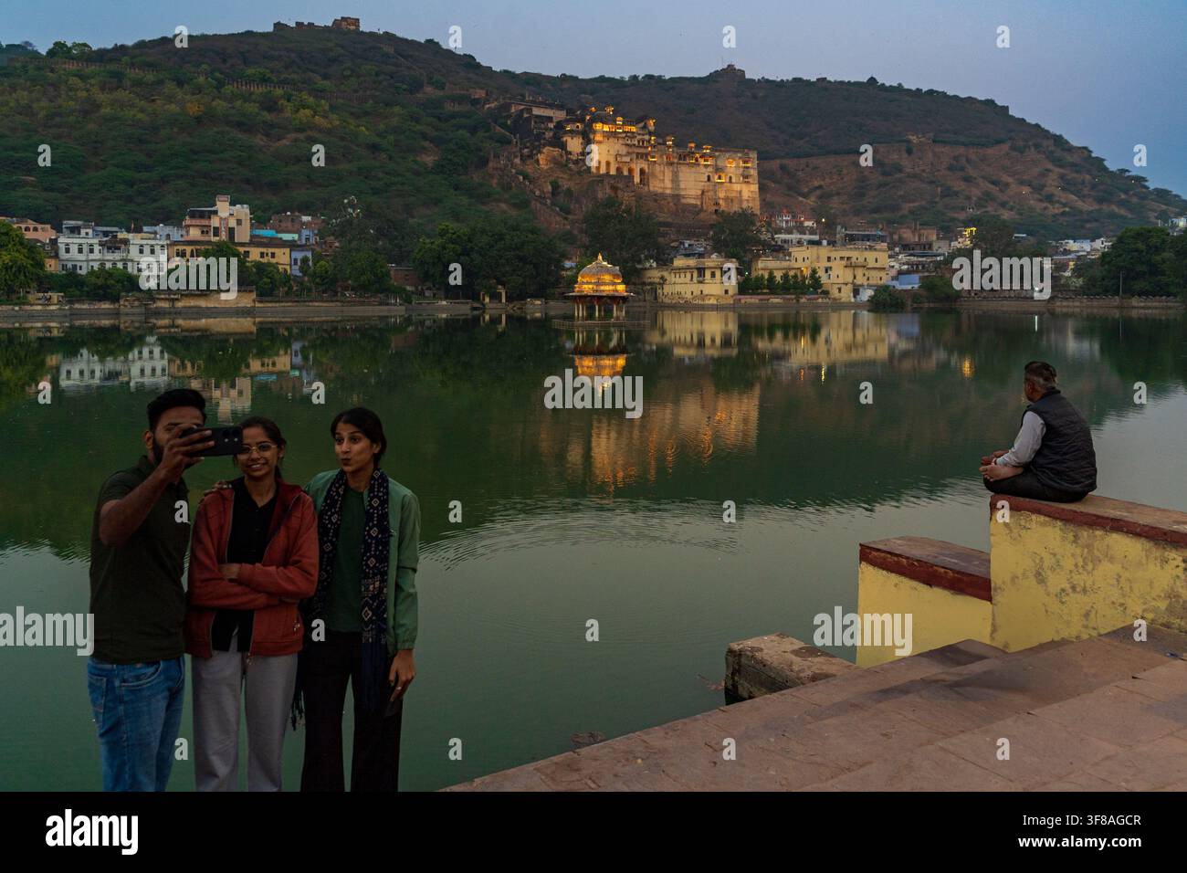 India. Rajasthan. Bundi. Un gruppo di giovani si scatta un selfie sul bordo del lago Nawal Sagar, di fronte al Garh Palace illuminato // India. Rajasthan. Bundi. Foto Stock