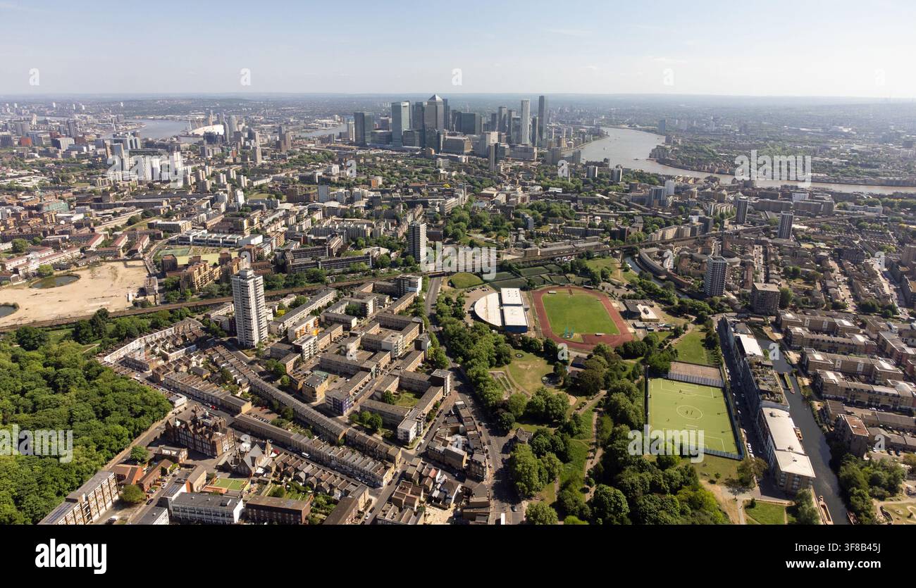 Vista aerea di Mile End, Londra: Mile End Park e lo stadio circondati da abitazioni diverse, con lo skyline di Canary Wharf in lontananza. Foto Stock