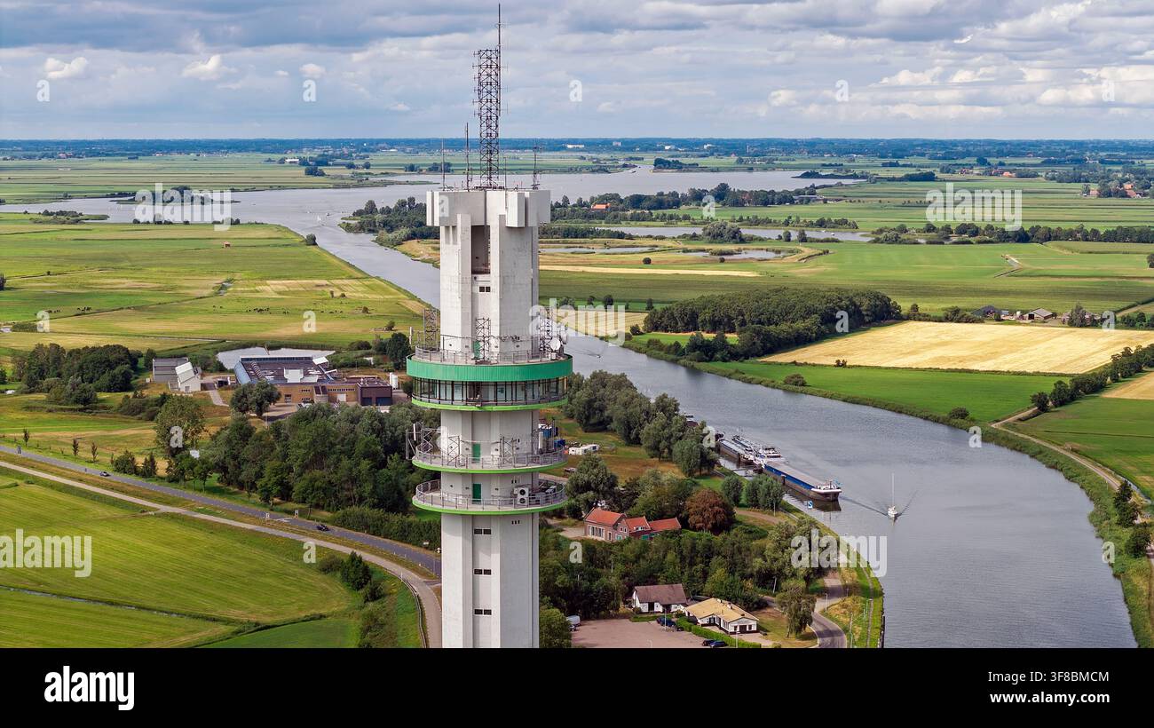 Vista aerea della torre di comunicazione e del centro dati ViaData Toren che si erge sopra i campi verdi, il canale e il paesaggio rurale di Tjerkgaast, Frisia Foto Stock