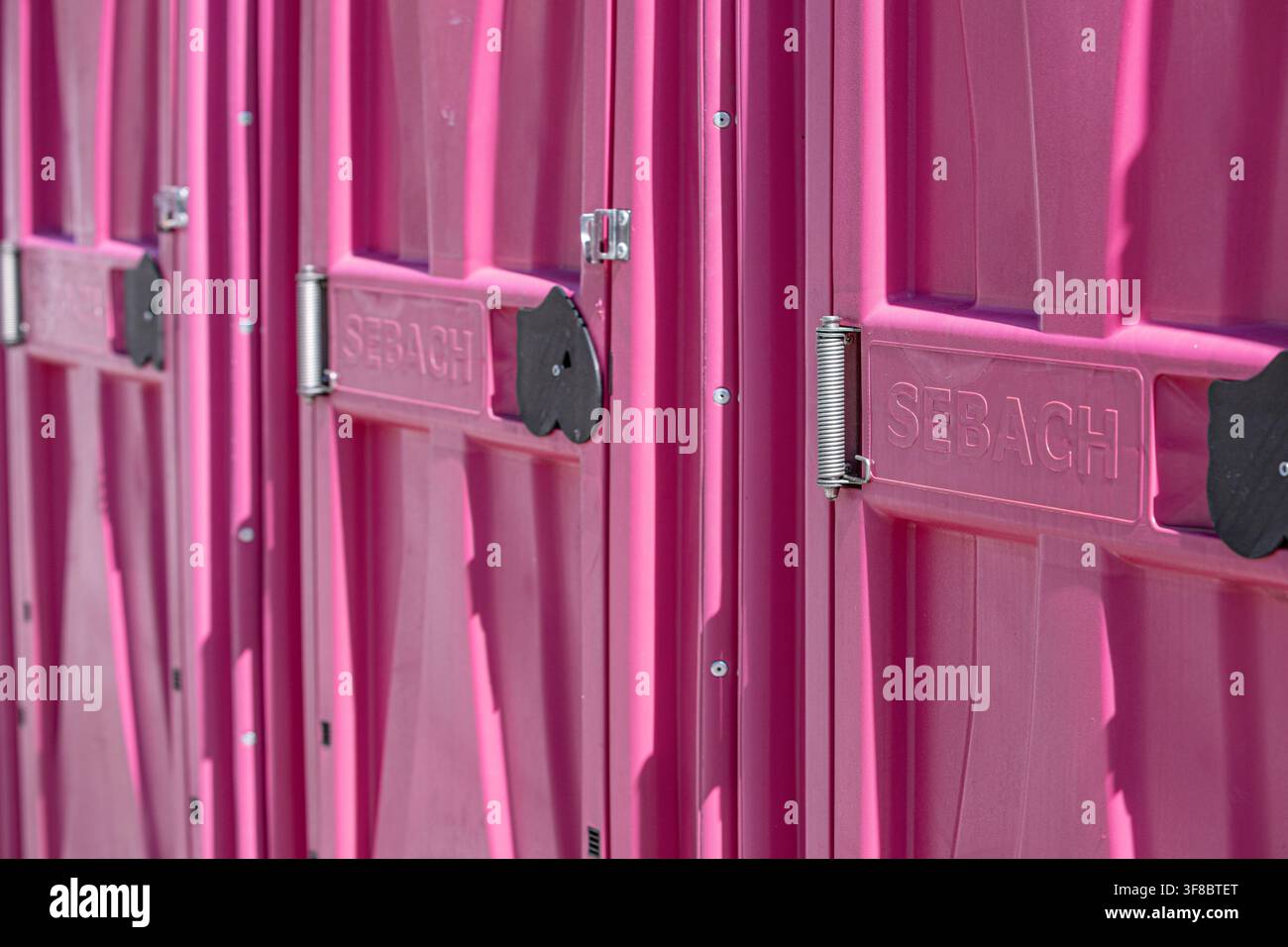 Prima piano delle porte in plastica dei bagni bio moderni Sebach con enfasi su cardini resistenti, serrature nere ergonomiche e alta qualità di assemblaggio. Foto Stock