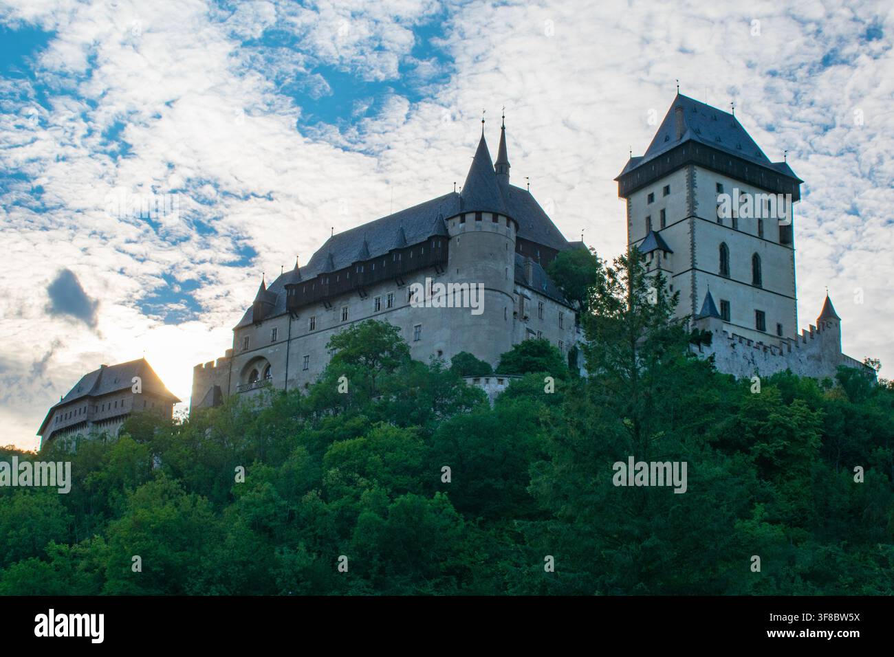 Le torri del castello di Karlstejn si ergono su una collina boscosa al tramonto nella Repubblica Ceca Foto Stock