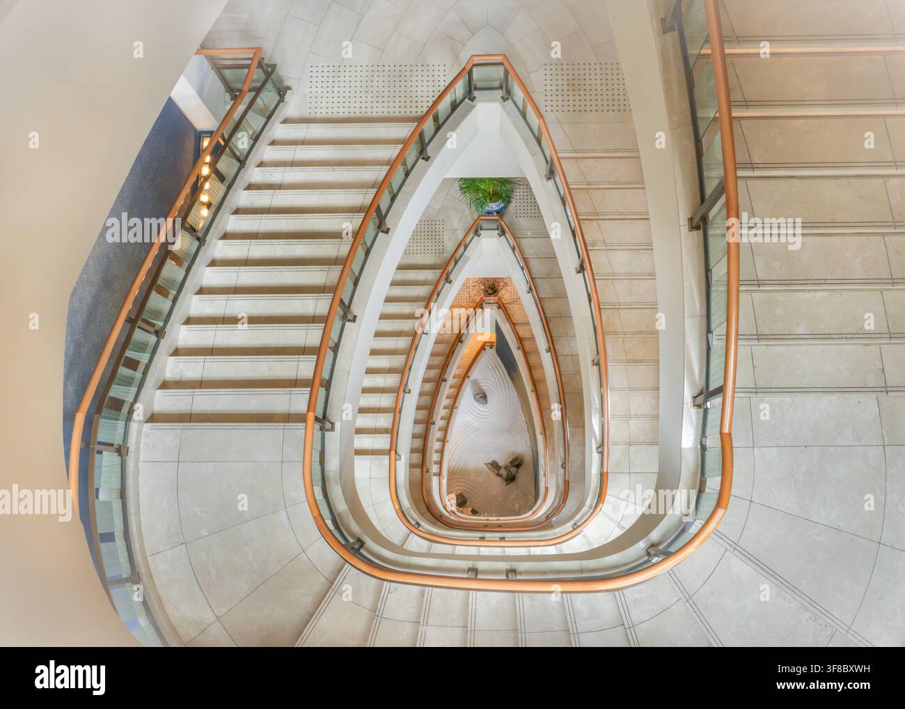 Vista dell'elegante scala a chiocciola con gradini in marmo e ringhiere in legno al The Peninsula Tokyo, Chiyoda City, Tokyo, Giappone. Foto Stock