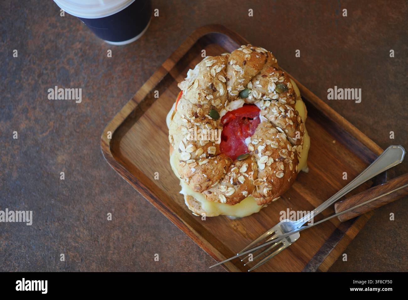 Delizioso panino su piatto di legno con bevanda nelle vicinanze Foto Stock