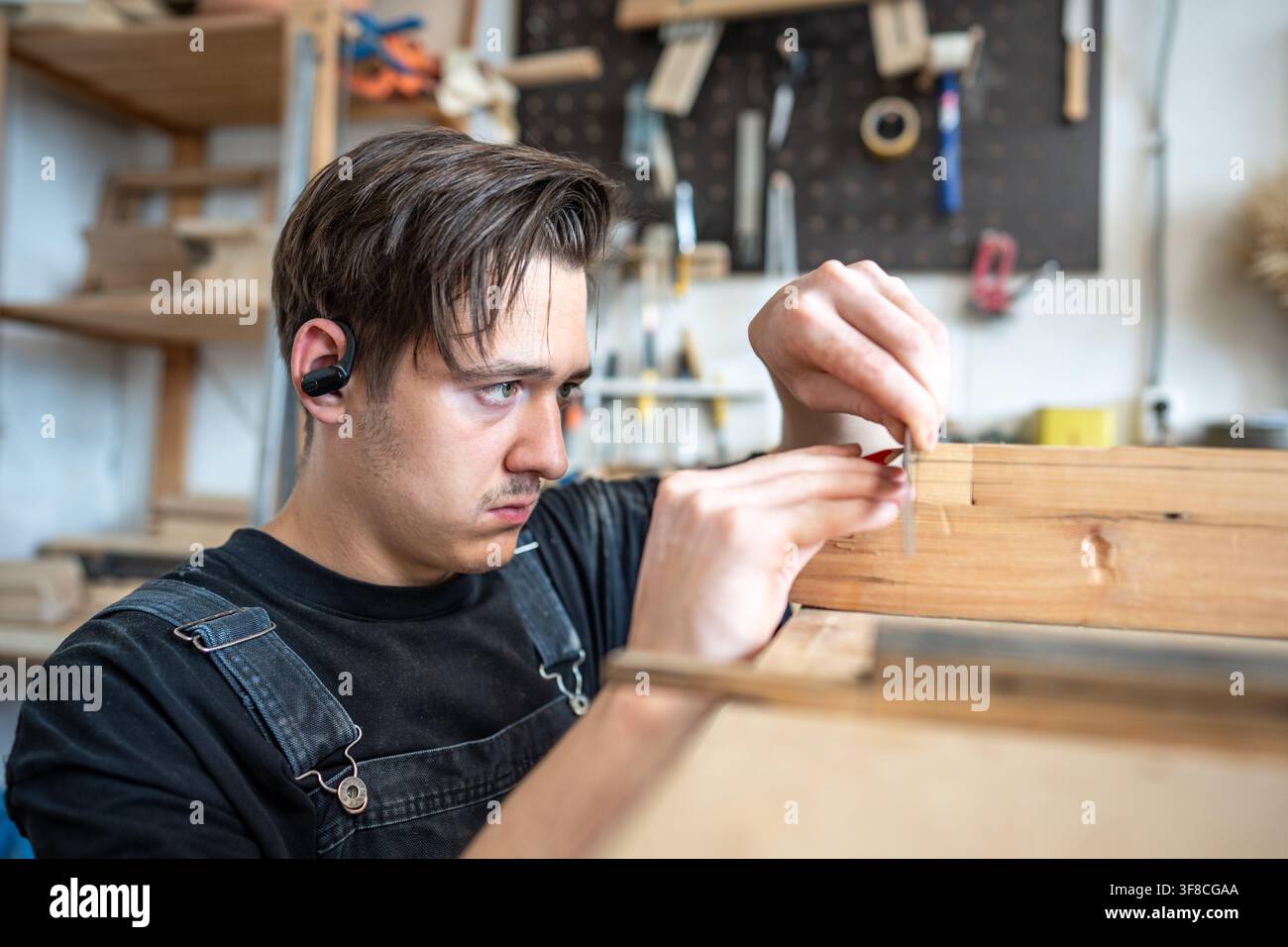 Restauratore professionista concentrato che esegue misurazioni su una toppa su una cornice di finestra vintage al tavolo Foto Stock