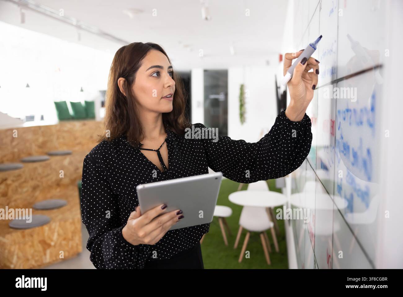 Donna d'affari sicura di sé che scrive una strategia sulla lavagna Foto Stock