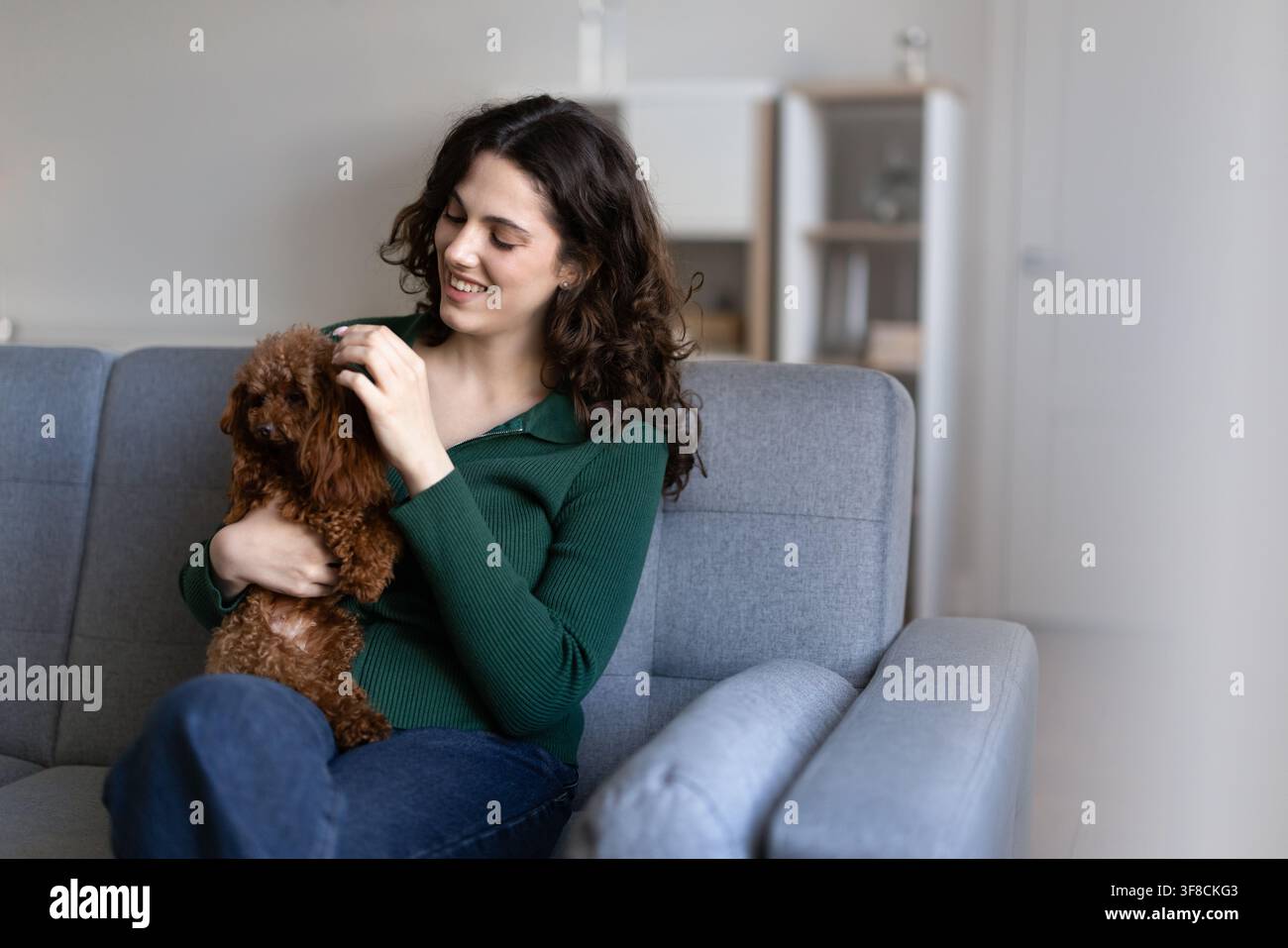 Donna che accarezza dolcemente un cane poodle, esprime amore, mostra affetto Foto Stock