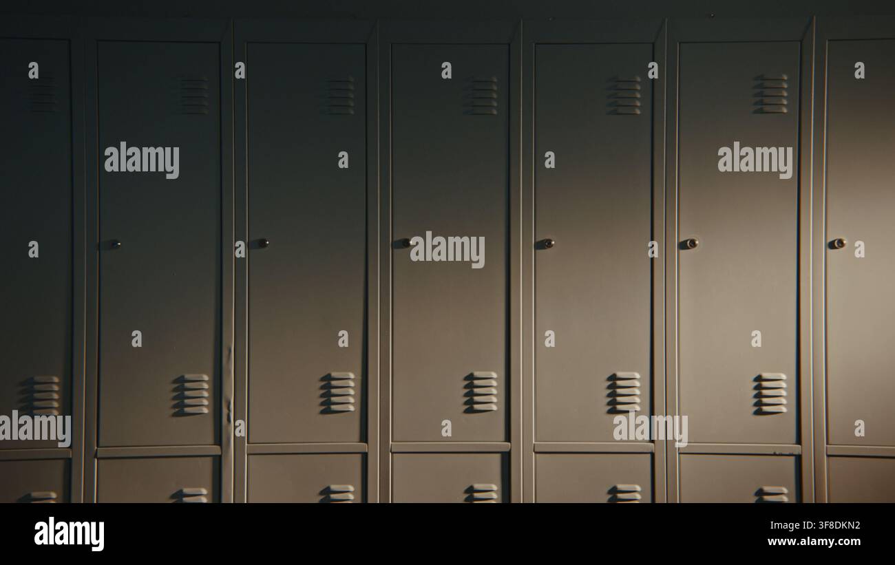 File ordinate di armadietti chiusi creano uno sfondo minimalista nel corridoio della scuola. Contenuto educativo versatile che rappresenta organizzazione, struttura, sicurezza, la vita accademica quotidiana senza persone. Foto Stock