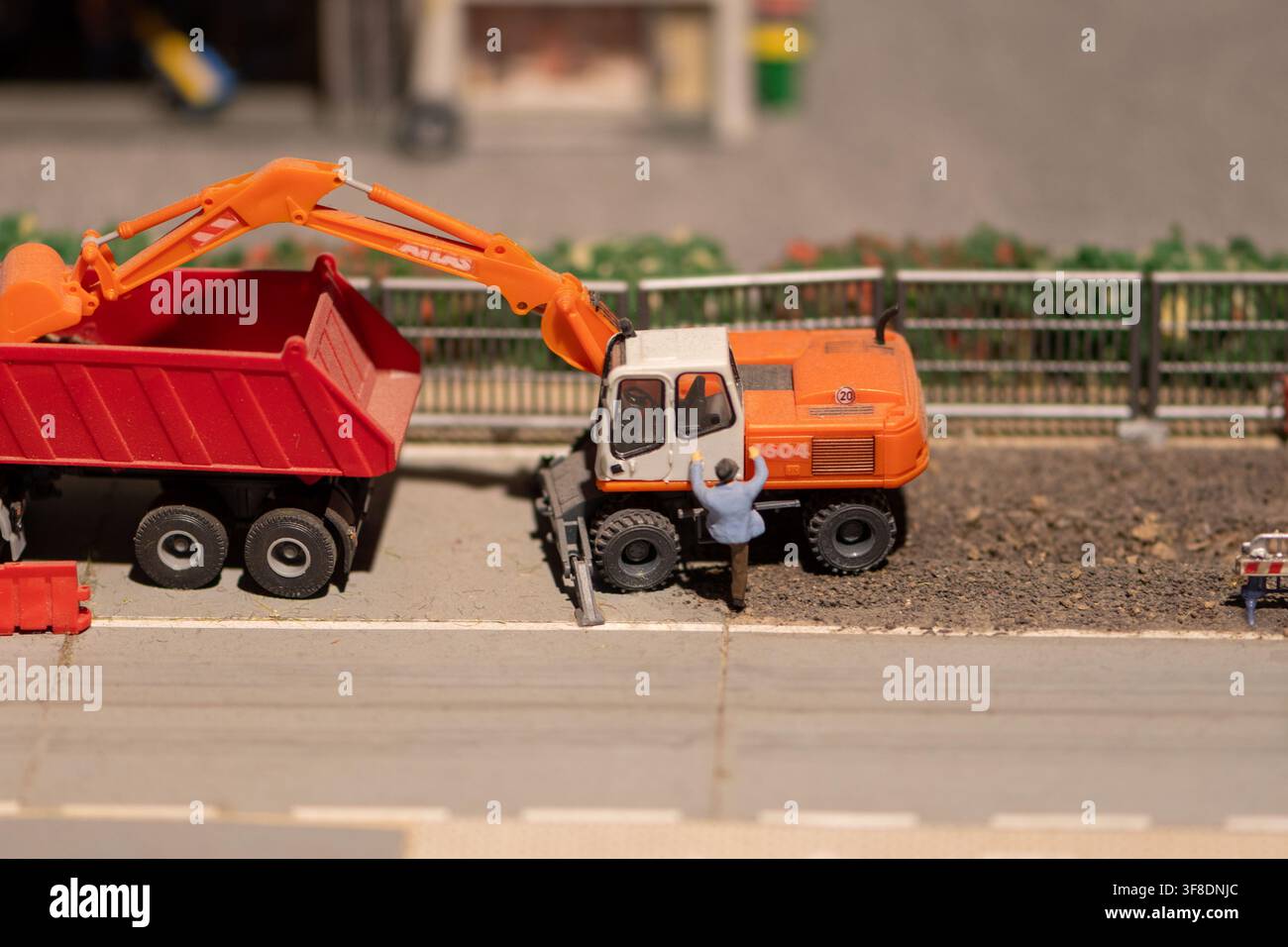 VIENNA, AUSTRIA, 26 novembre 2022: Un primo piano di una scena di diorama mostra un escavatore arancione in miniatura accanto a un camion ribaltabile rosso con una piccola figura di un operaio accanto Foto Stock