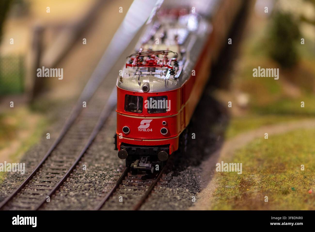 VIENA, AUSTRIA, 26 novembre 2022 : Un modello di locomotiva elettrica in miniatura rossa è fotografato di fronte su binari ferroviari dettagliati con uno sfondo sfocato Foto Stock