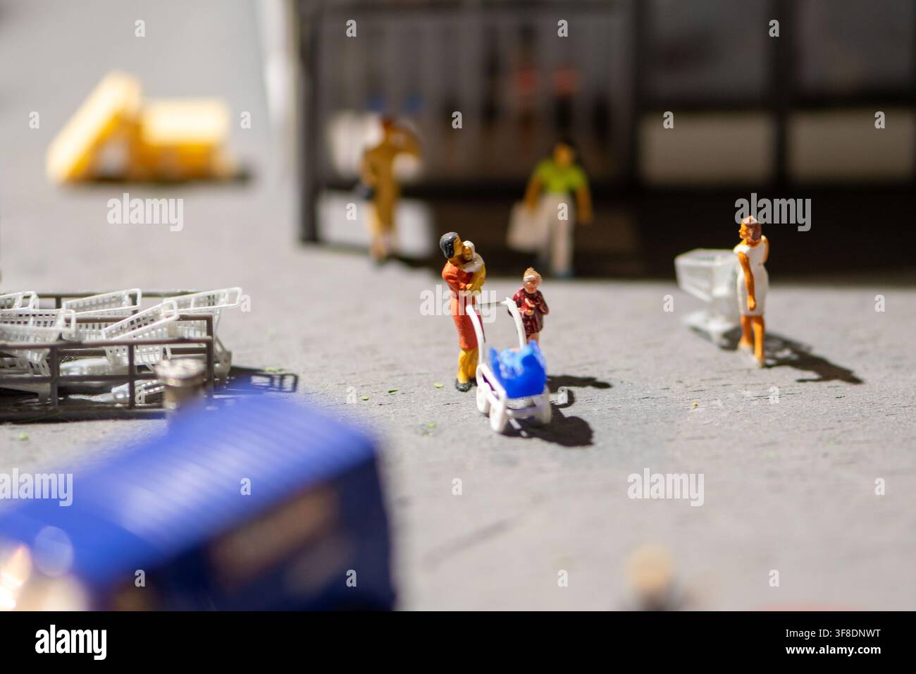 Una scena di diorama in primo piano mostra minuscole figurine di acquirenti, carrelli della spesa e un passeggino vicino all'ingresso di un negozio. Foto Stock