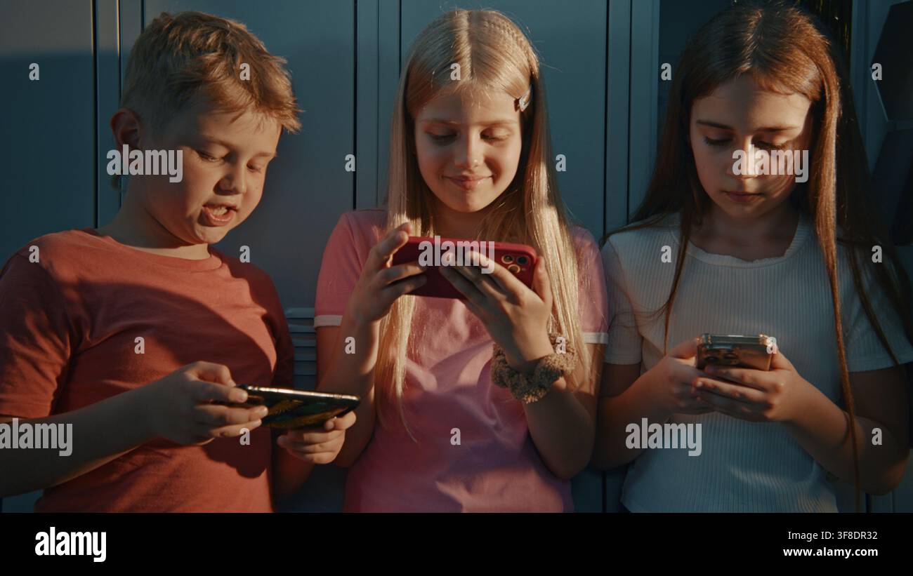 Compagni di classe concentrati sui dispositivi mobili. Esperienza moderna del ritorno a scuola. Concetti relativi alla sicurezza su Internet, alla sensibilizzazione sul cyberbullismo, alla tecnologia educativa e alla vita scolastica quotidiana della generazione Alpha. Foto Stock