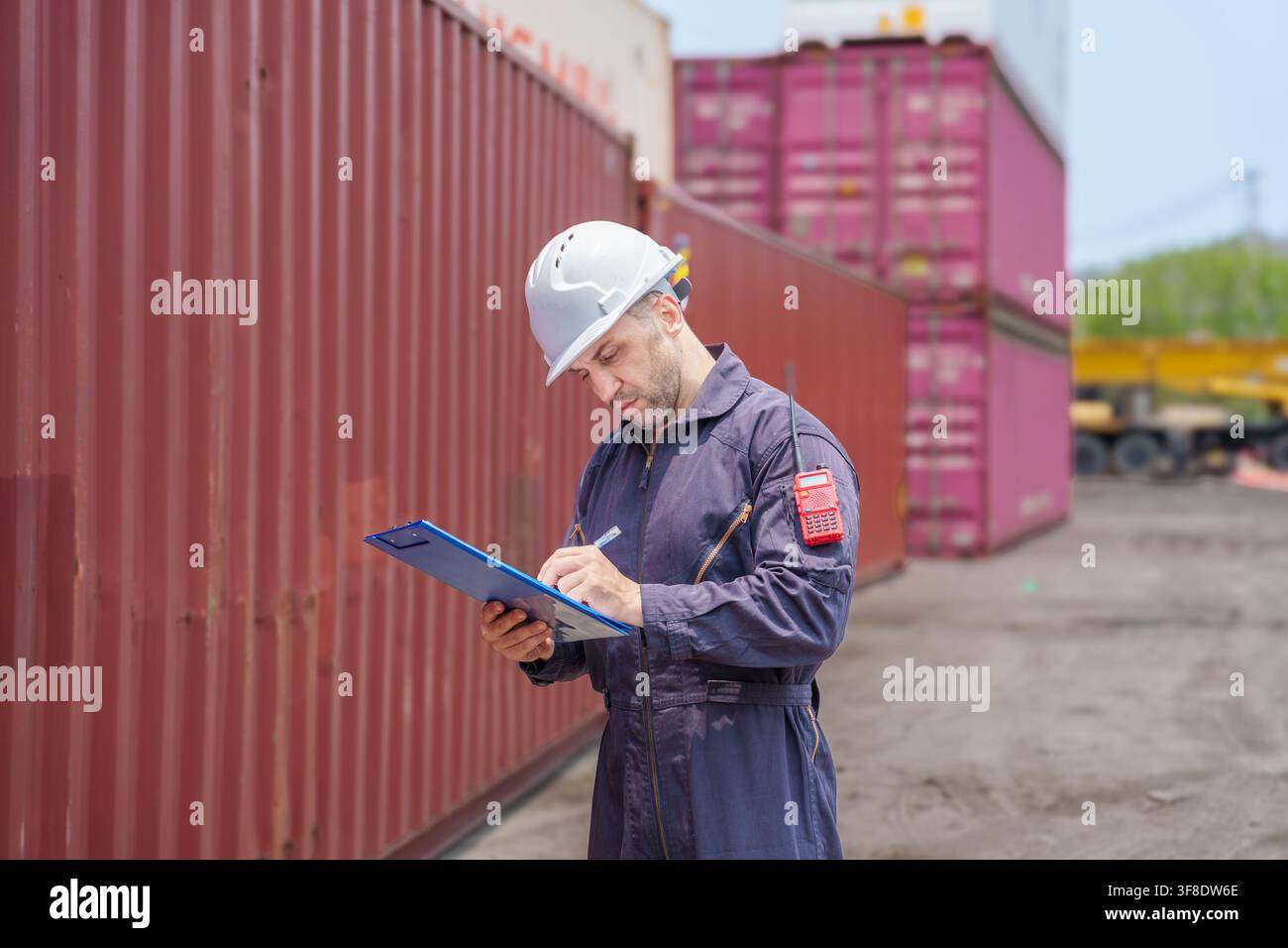 Lavoratore portuale che esegue l'ispezione sui container di spedizione nel porto per una gestione logistica efficace. Ideale per trasporto, logistica e approvvigionamento Foto Stock