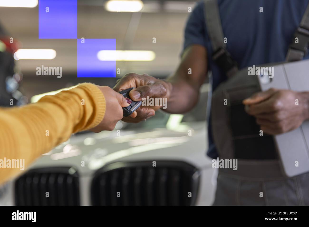Meccanico e cliente soddisfatto in un'officina moderna. Le chiavi dell'auto vengono restituite dopo aver completato la manutenzione e la riparazione. Foto Stock