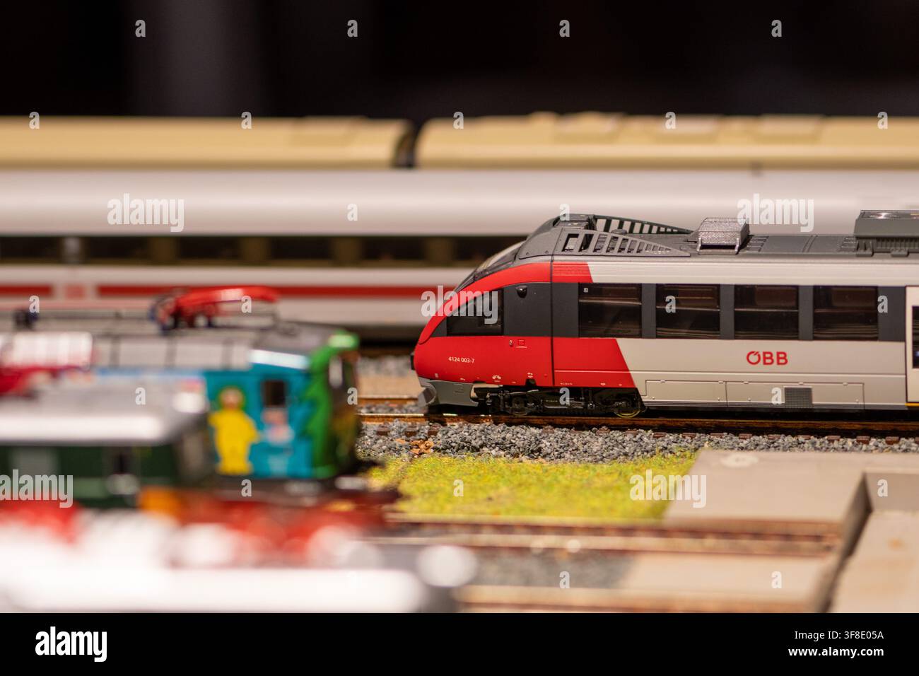 VIENA, AUSTRIA, 26 novembre 2022: Un treno passeggeri modello OBB rosso e grigio è fermo sui binari all'interno di un layout ferroviario in miniatura con treni sfocati in Foto Stock