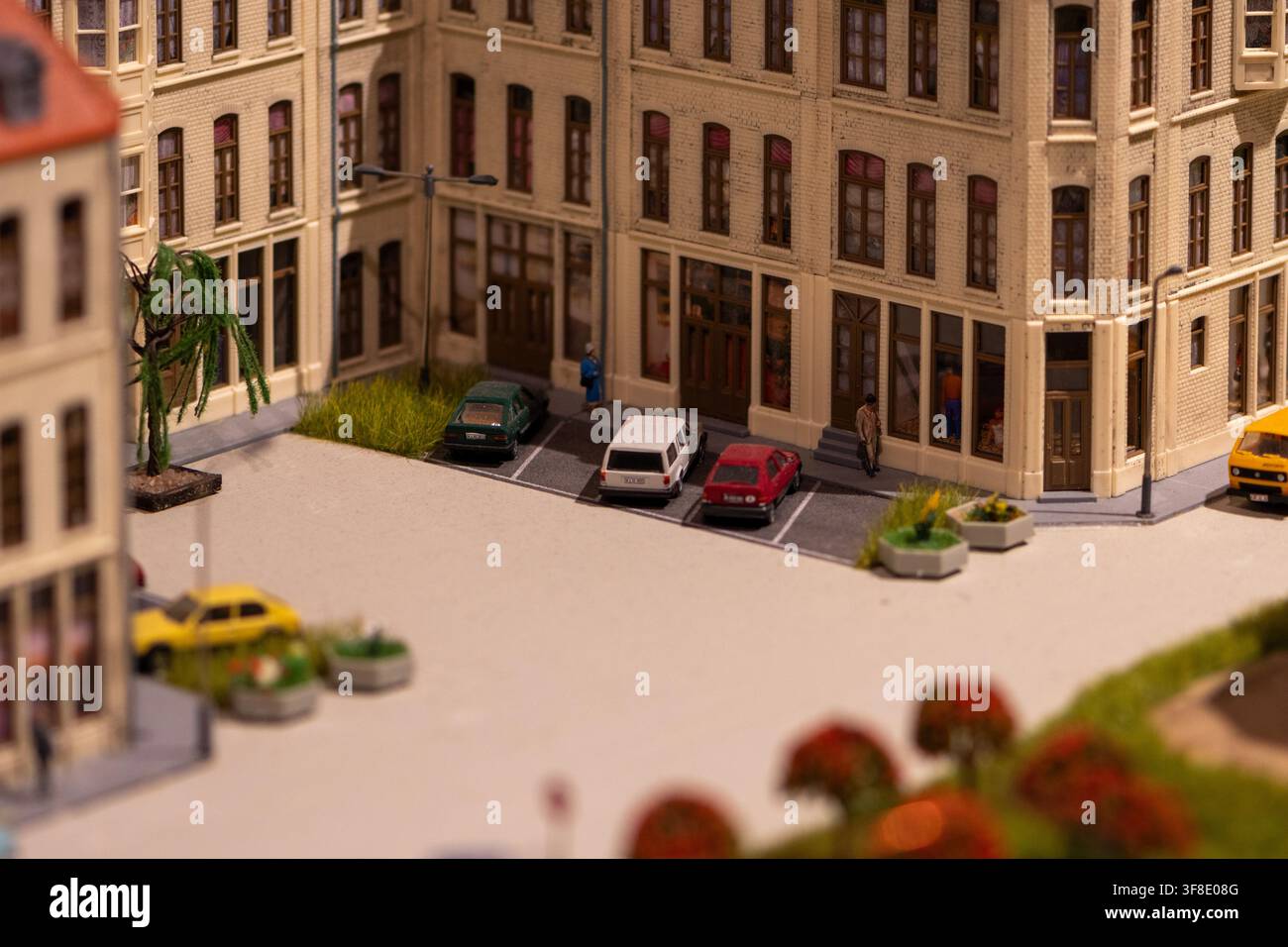 Un diorama urbano dettagliato mostra edifici a più piani, auto parcheggiate, piccole statuette e una scena di cortile con messa a fuoco superficiale. Foto Stock
