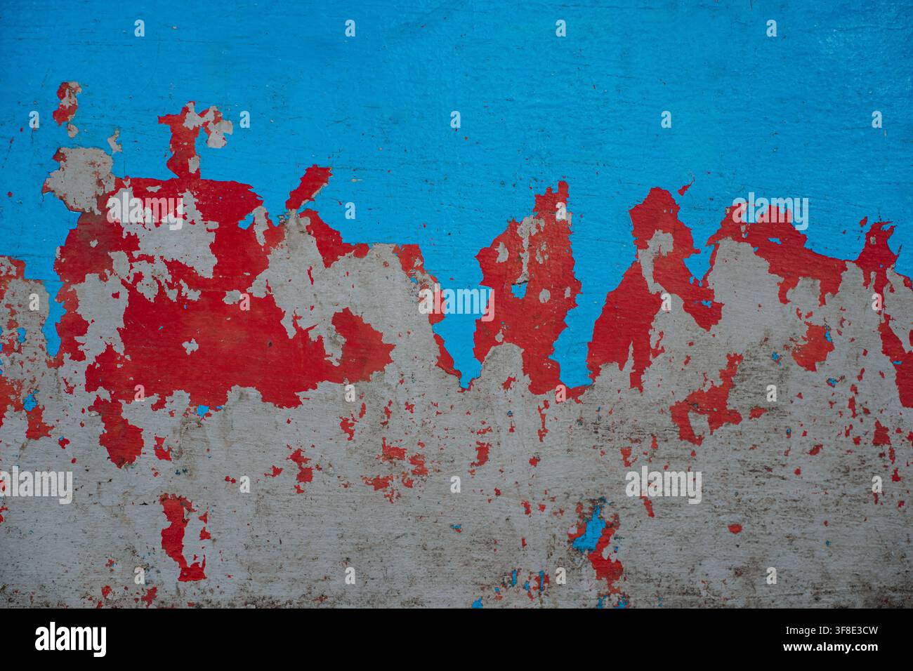 Vernice rossa e blu scrostata su vecchio muro di cemento, sfondo texture grunge. Foto Stock