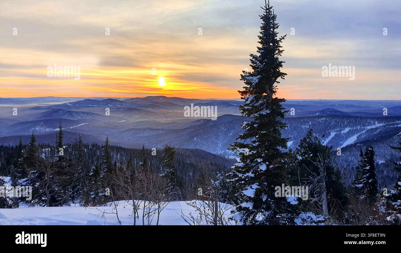 Tramonto tra le montagne in inverno. Fantastico paesaggio invernale serale. Cielo drammaticamente coperto. College creativo. Il mondo della bellezza. Foto Stock