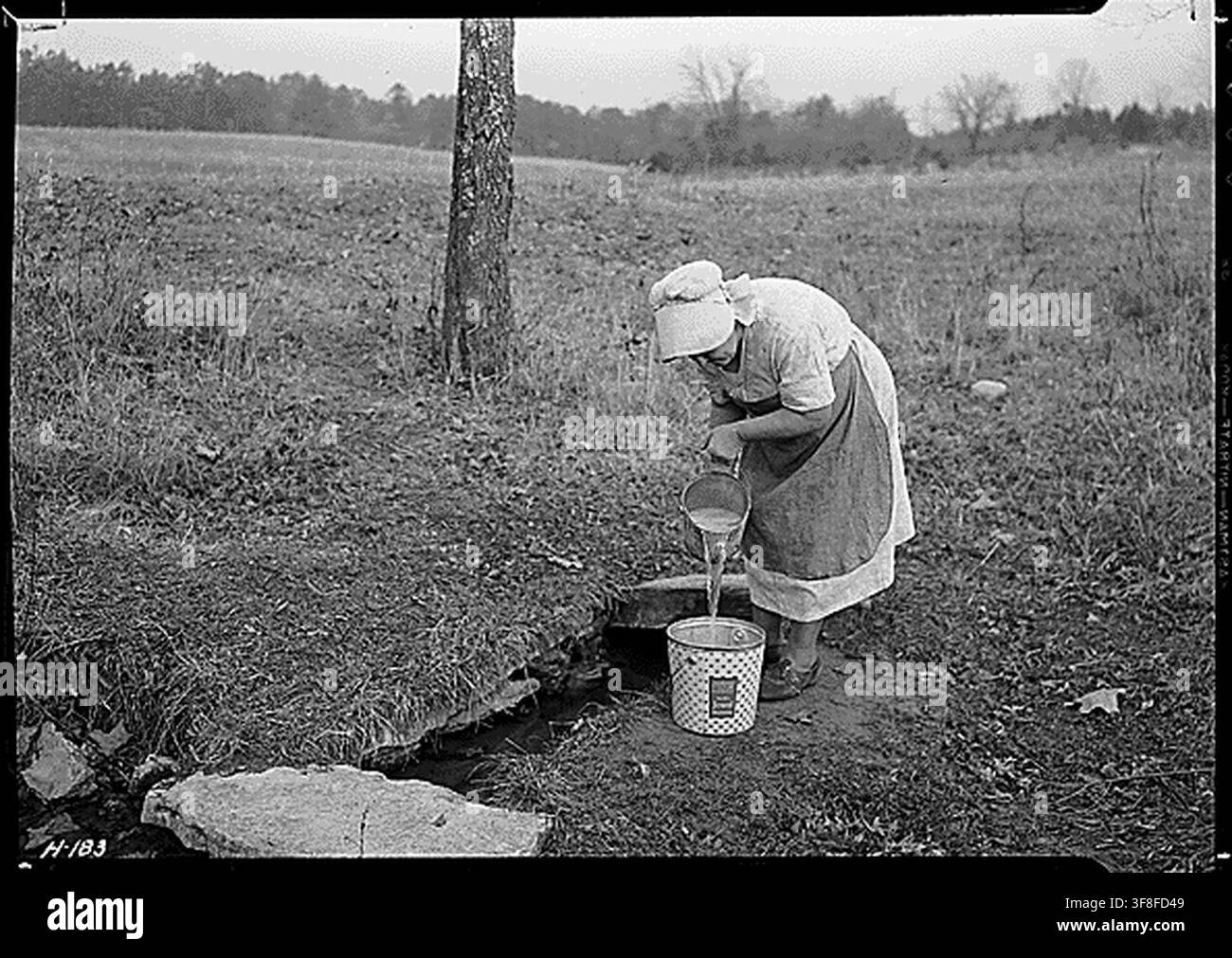 La signora Wallace raccoglie acqua da una sorgente in una fattoria vicino alla città di Norris, recentemente acquistata dalla Tennessee Valley Authority a scopo sperimentale, da Lewis Hine il 24 novembre 1933. Foto Stock