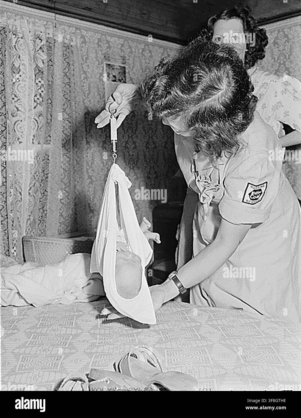 Miss Hazel Jamison, infermiera registrata impiegata dalla Koppers Coal Company, pesa il bambino di Aubrey Cook, un minatore, a casa sua a Kopperston, Contea di Wyoming, Virginia Occidentale, nell’ambito dei suoi doveri di salute pubblica, che includono assistenza prenatale e post-partum, corsi di infermieristica domestica e immunizzazione, il 22 agosto 1946. Foto Stock
