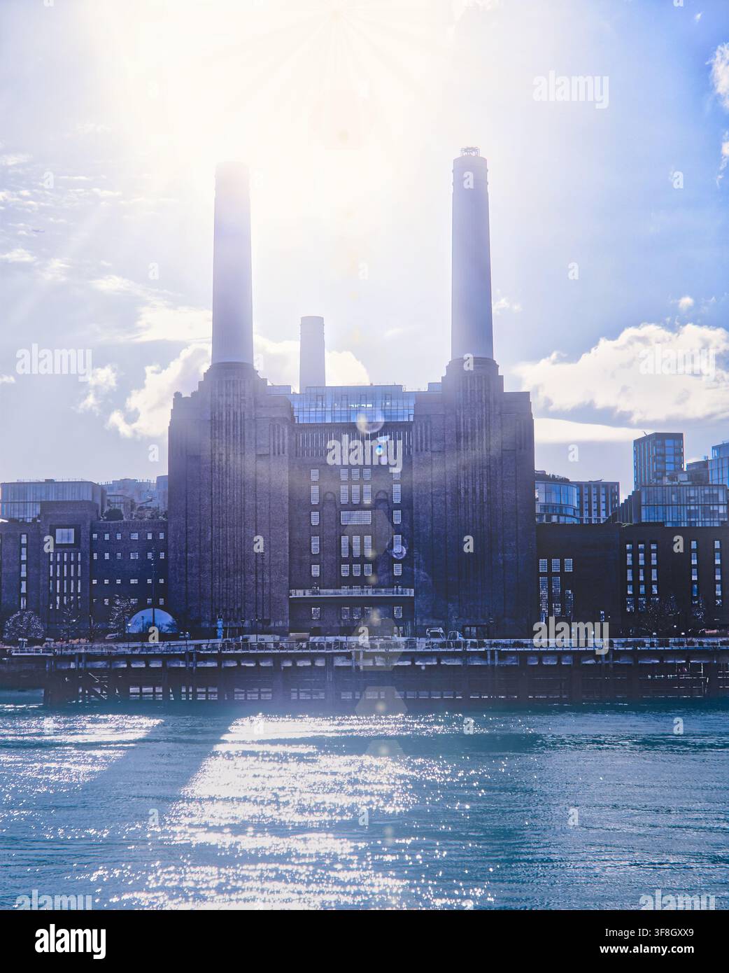 L'imponente facciata della Battersea Power Station nel sud-ovest di Londra con i suoi due alti camini sembra quasi scomparire, sagomata contro il bagliore Foto Stock