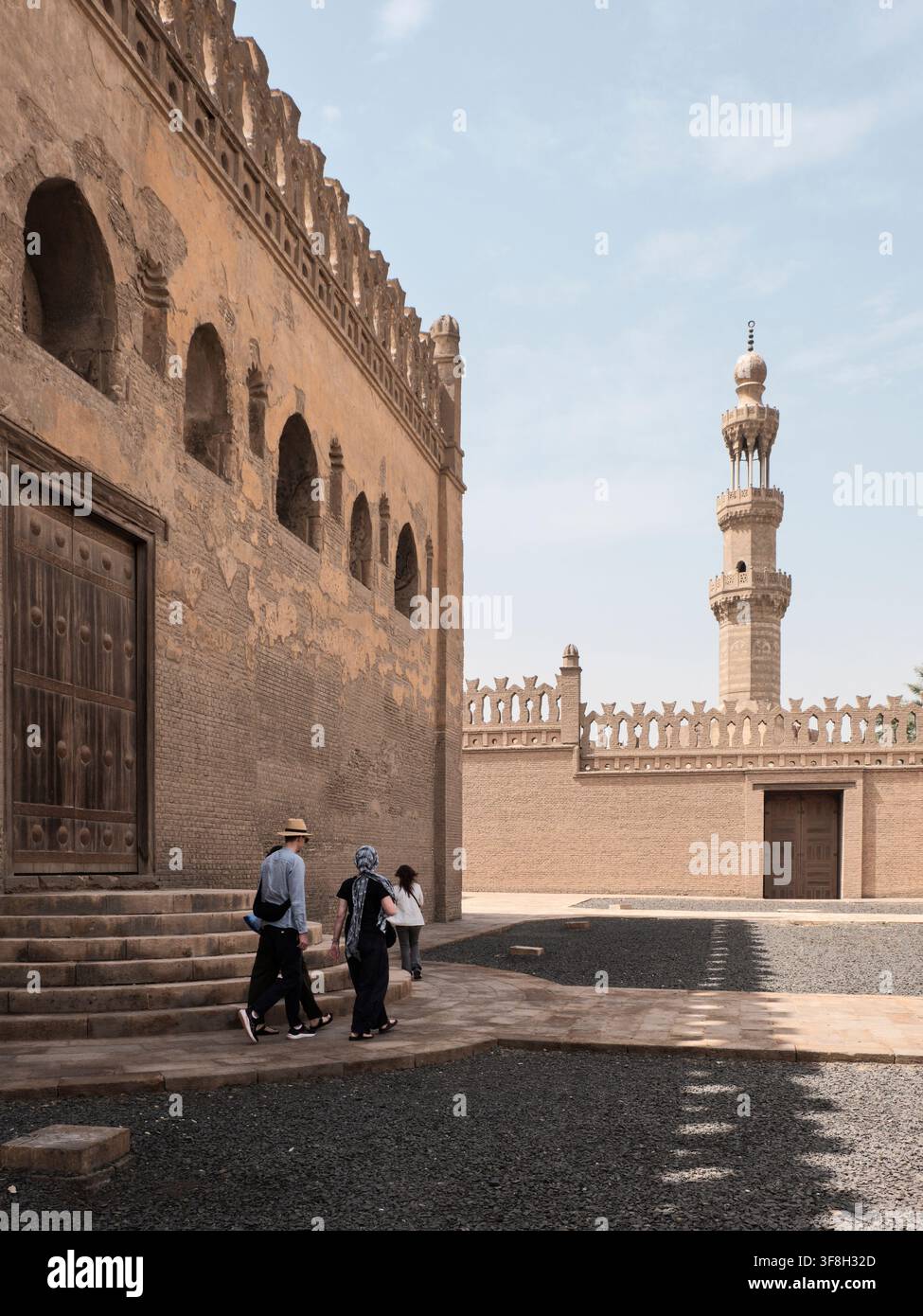 Tre viaggiatori ammirano il minareto storico della Moschea di Ibn Tulun del IX secolo al Cairo, Egitto. Fotografia di viaggio verticale a colori Foto Stock