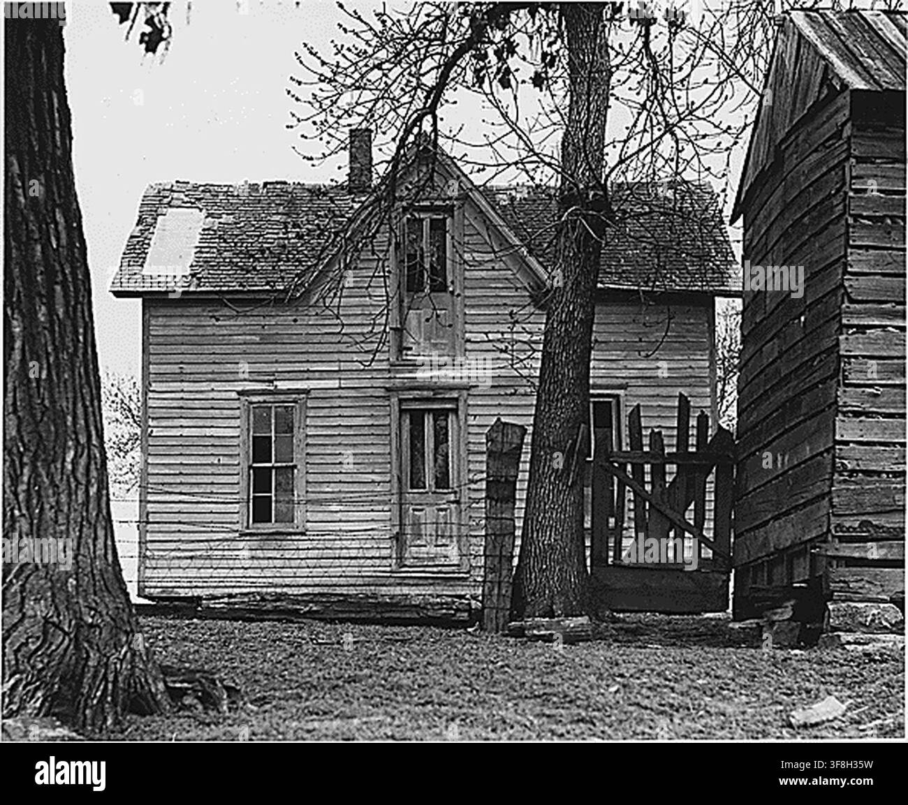 Una casa abbandonata nella contea di Shelby, Iowa, dove l'abbandono è raro, con il terreno circostante e alcune dependance ancora in uso, dal Bureau of Agricultural Economics. Foto Stock
