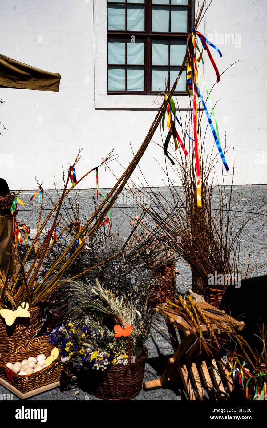 Rami di salice tradizionali per Pasqua decorati con nastri colorati esposti con cesti e decorazioni primaverili in un mercato all'aperto Foto Stock