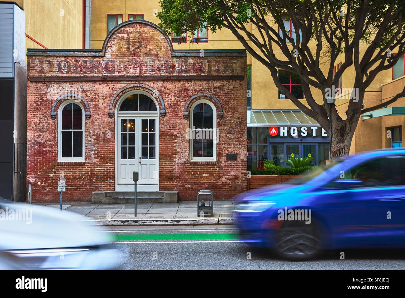 Ostello in edificio storico di mattoni e auto in movimento, scena stradale a Santa Monica Foto Stock