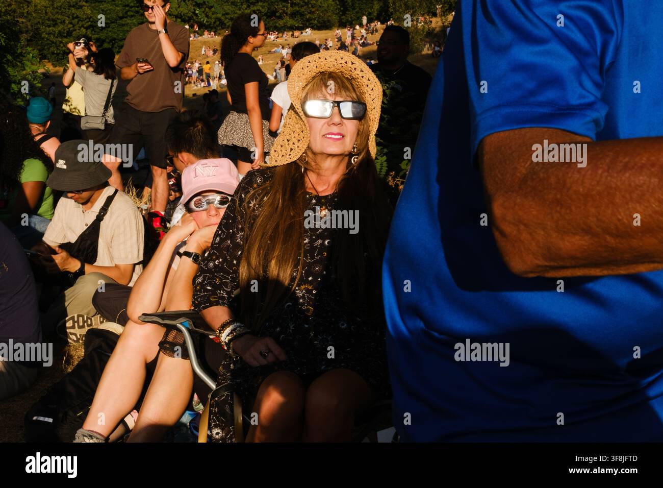 Gli spettatori osservano l'eclissi solare parziale a Londra il 12 agosto 2026. Le persone si sono radunate in uno spazio pubblico per assistere all'evento celeste. Foto Stock