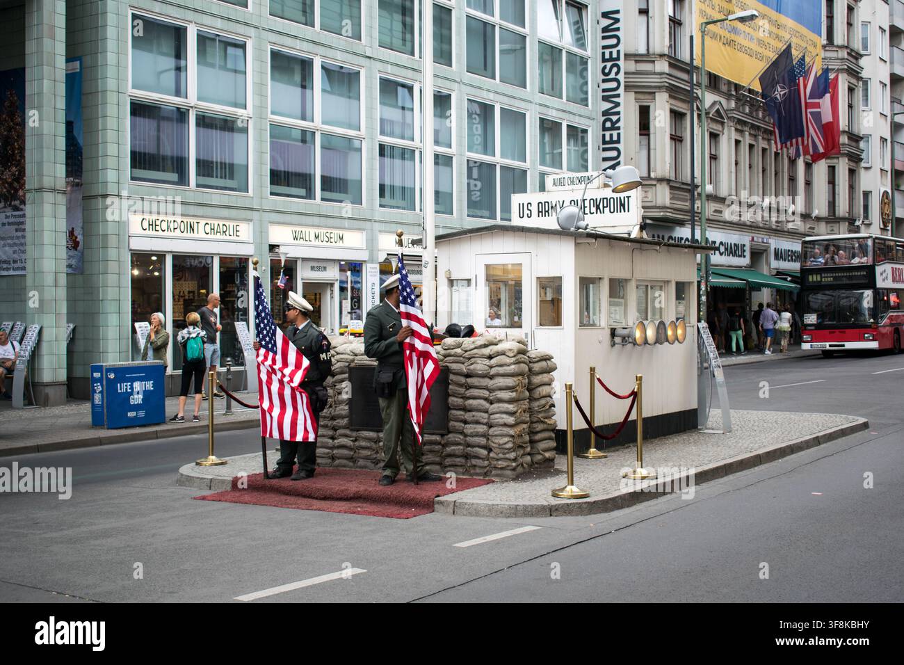Berlino, Germania - 11 agosto 2018: Attori vestiti da guardie di confine storiche posano per i turisti al punto di passaggio di Checkpoint Charlie. Foto Stock