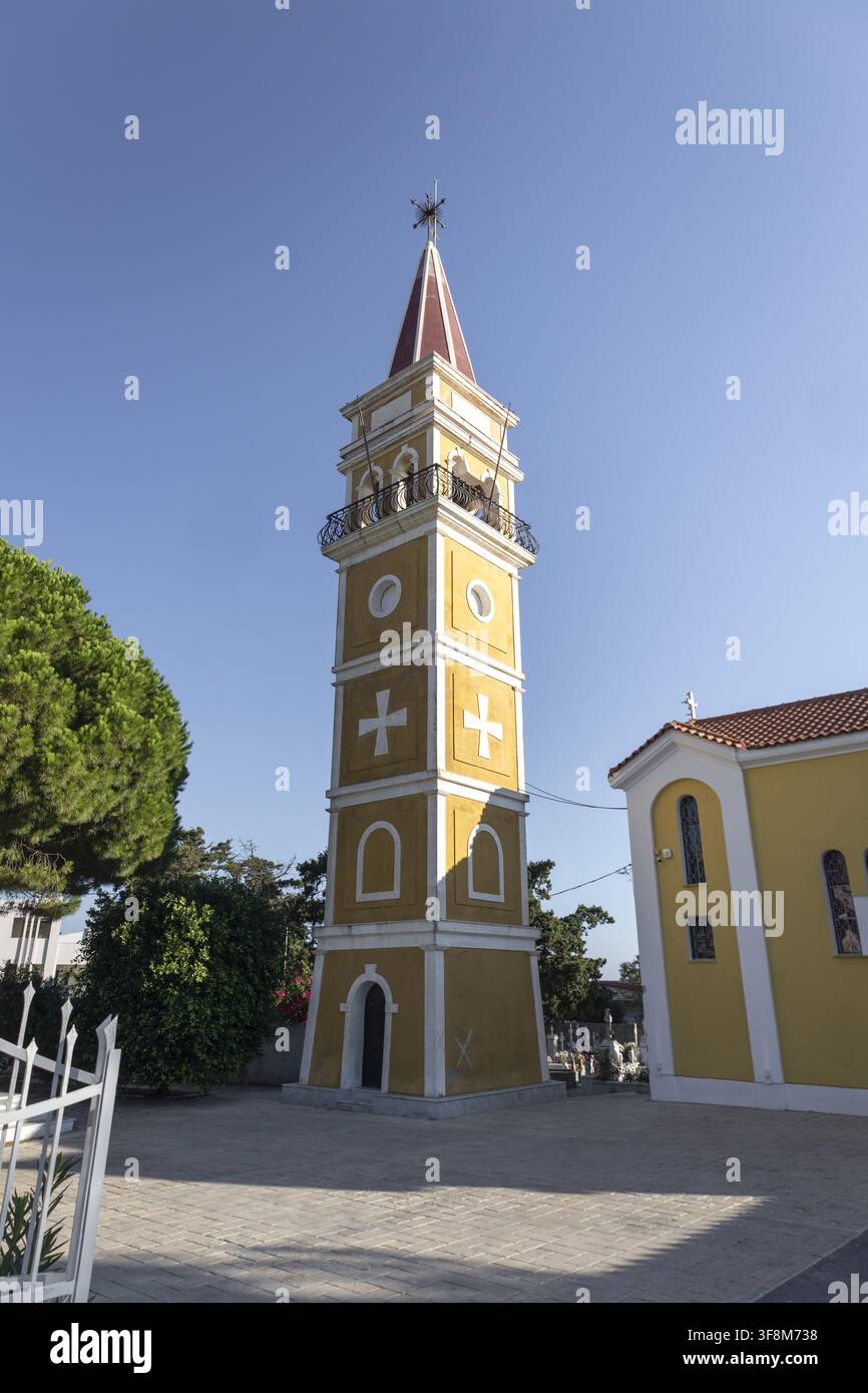 Vista del campanile giallo della chiesa con tetto rosso e croci bianche sotto un cielo blu limpido ad Argassi, Grecia. Foto Stock