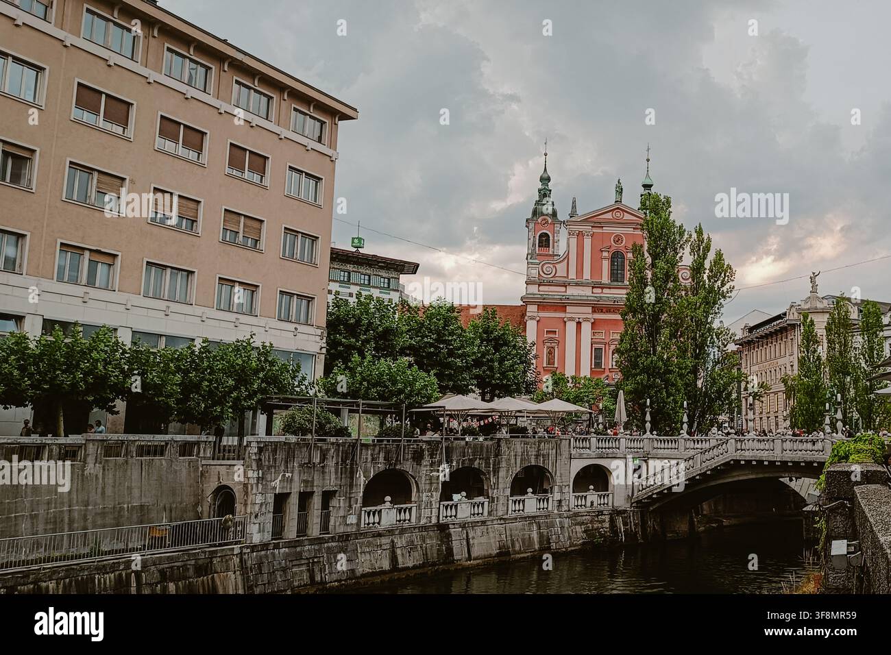 Ljubljana, Slovenia - 11 luglio 2026: Vista della Chiesa francescana dell'Annunciazione che si affaccia sul fiume Ljubljanica con il Ponte Triplo e suo Foto Stock