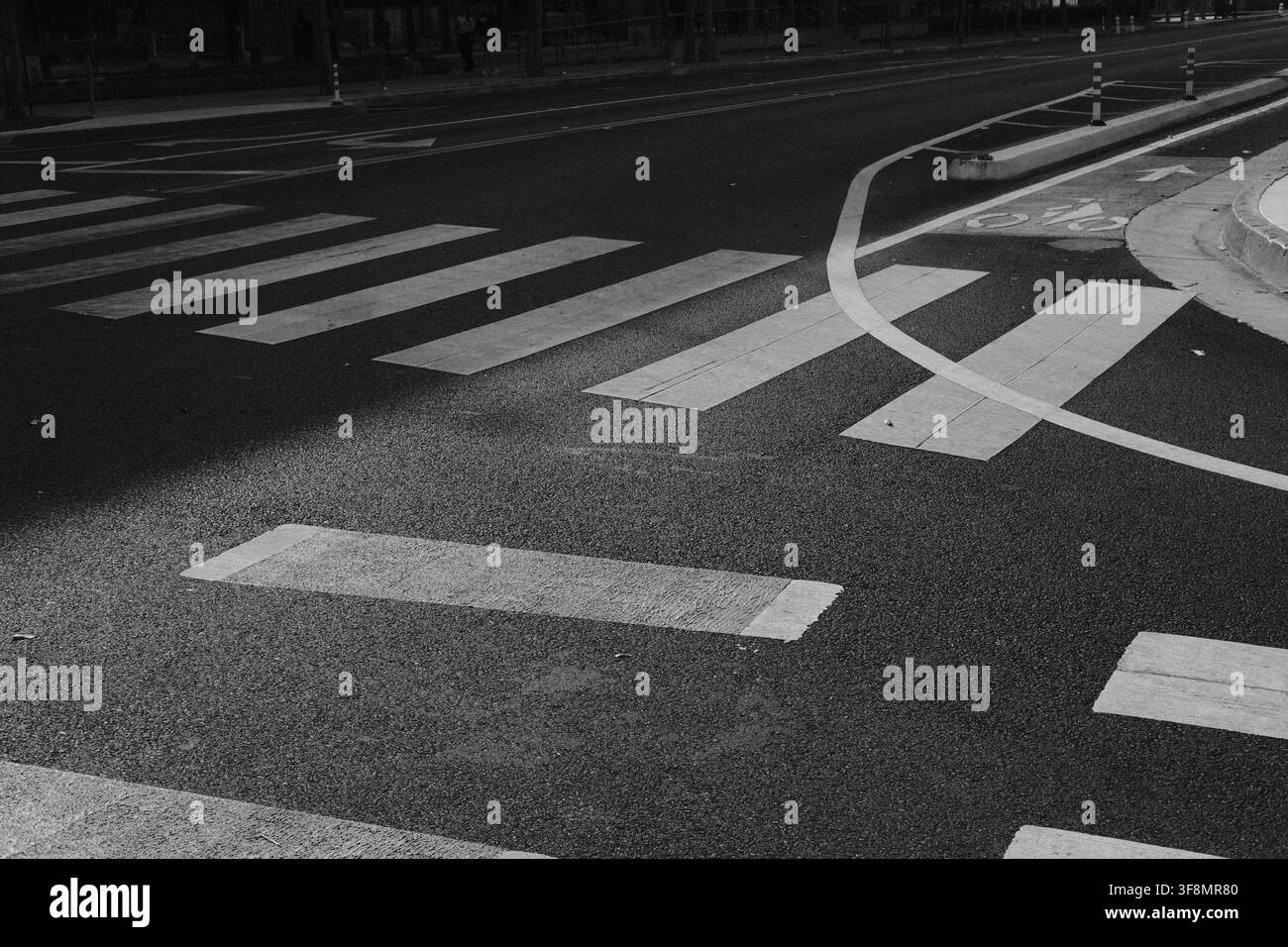 Passaggi pedonali dipinti, corsie di traffico e segnaletica stradale curva formano motivi geometrici a un incrocio urbano a Los Angeles, California. Foto Stock