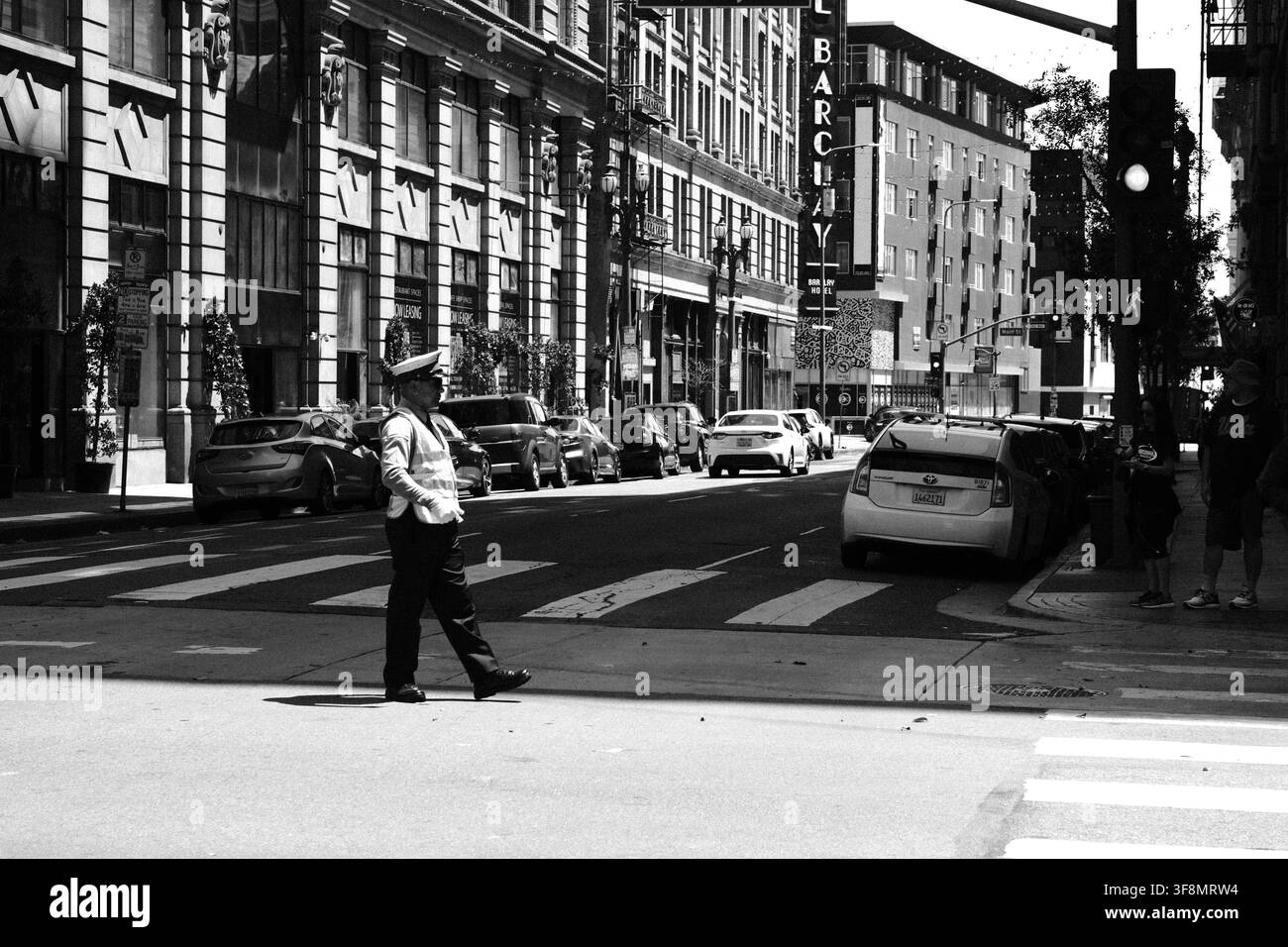 Guardia che attraversa un incrocio urbano circondato da edifici commerciali storici nel centro di Los Angeles, California. Foto Stock