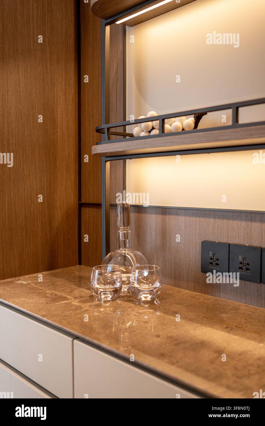 Caraffa di vetro e due bicchieri abbinati su un bancone moderno in marmo per minibar. Foto Stock
