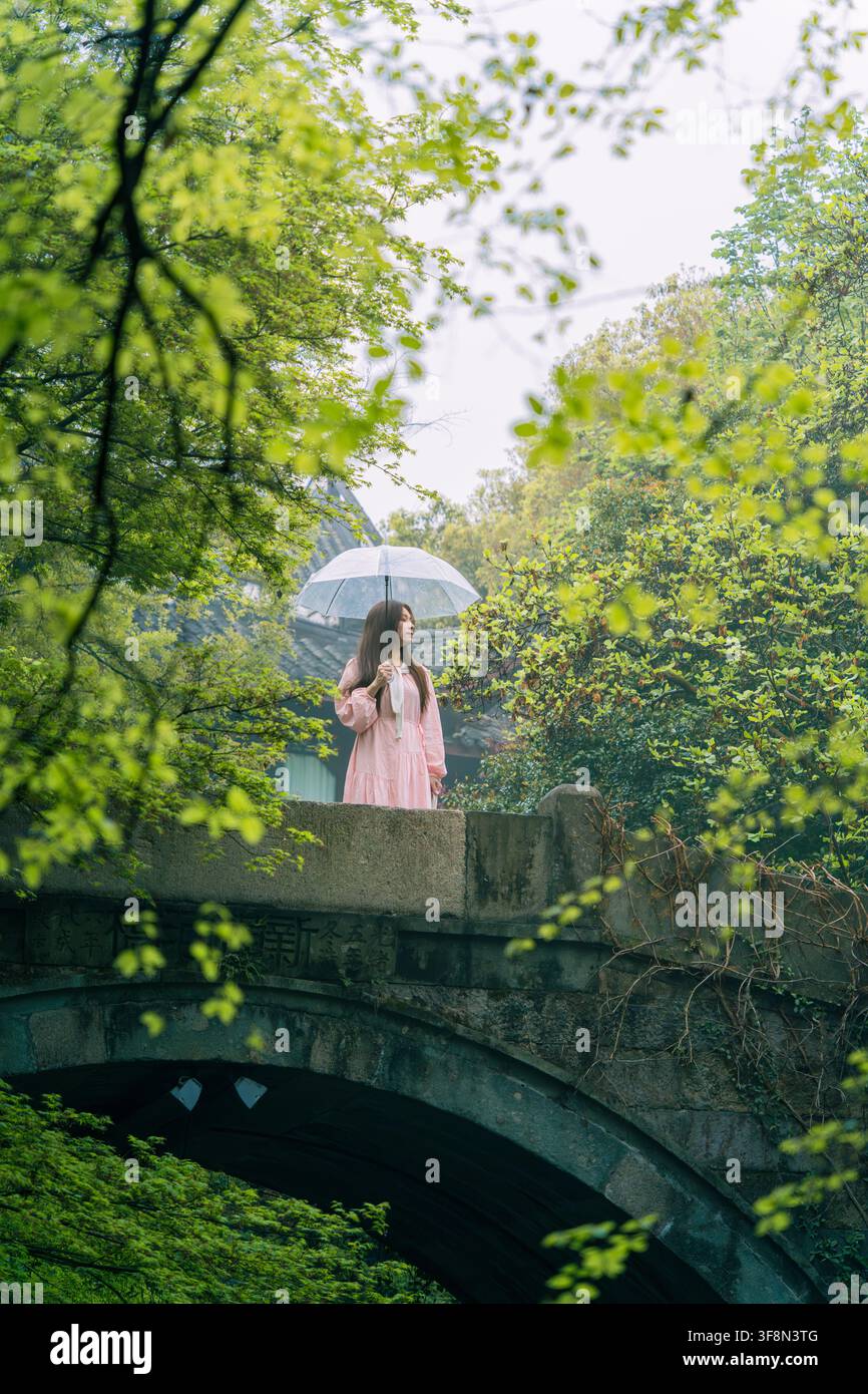 Donna con cappello che tiene un ombrello su un antico ponte di pietra, vista posteriore, Liulang Wenying, Hangzhou Foto Stock