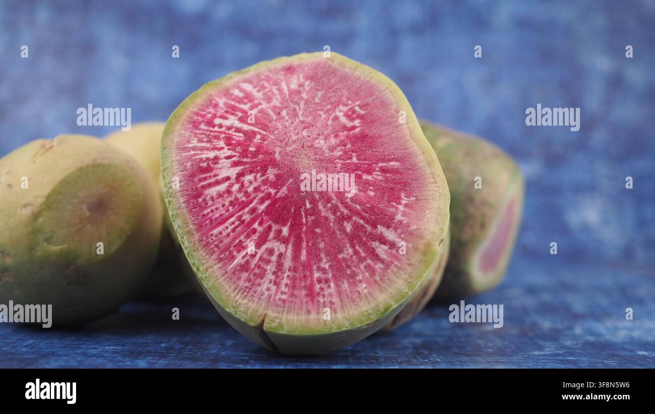Metà fresca di ravanello melone su sfondo blu Foto Stock